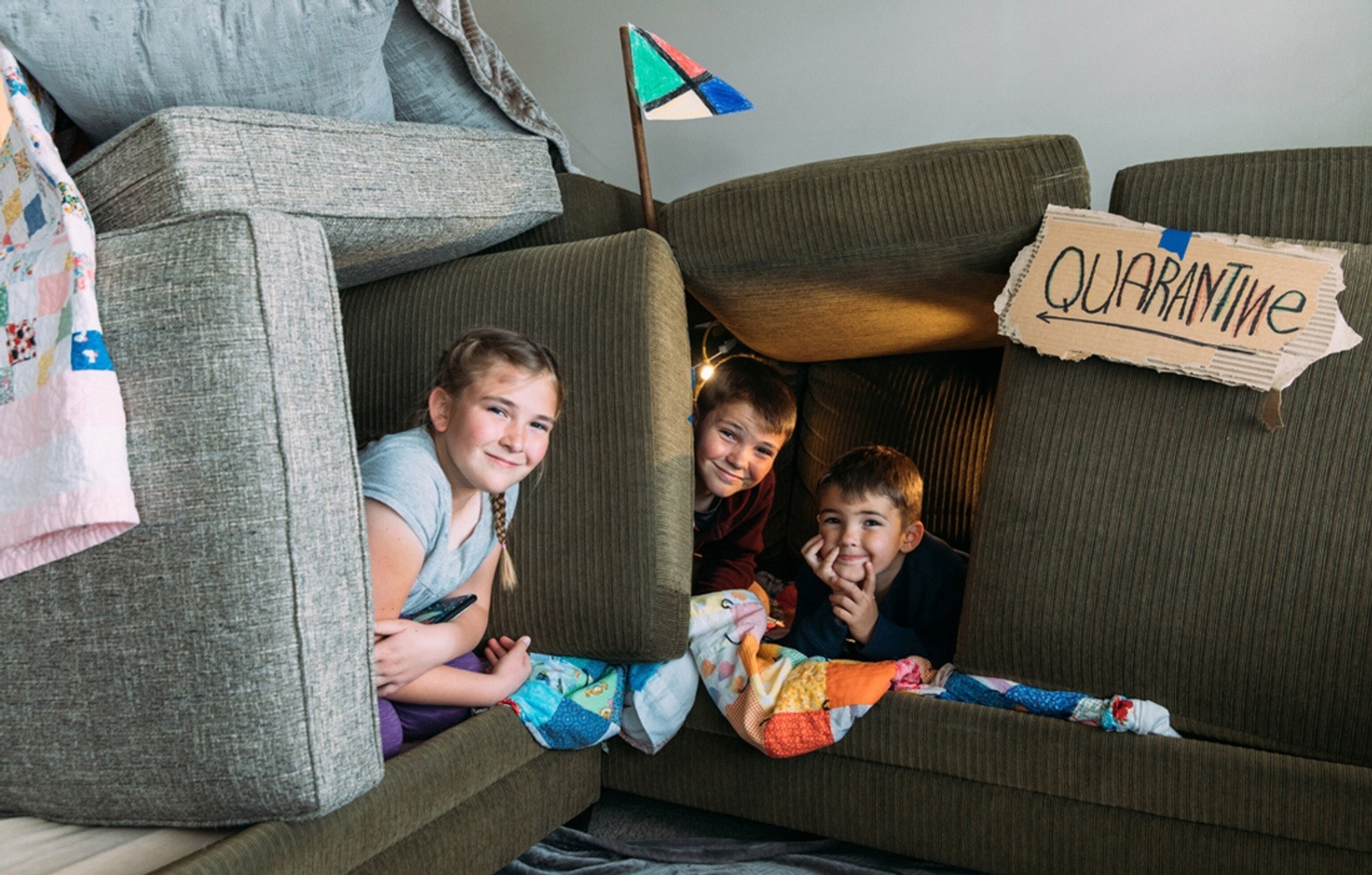 Young siblings, who are under a shelter in place order, are having fun in a couch fort quarantine.