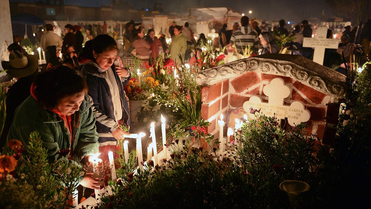 Family members light candles along a loved one's grave.
