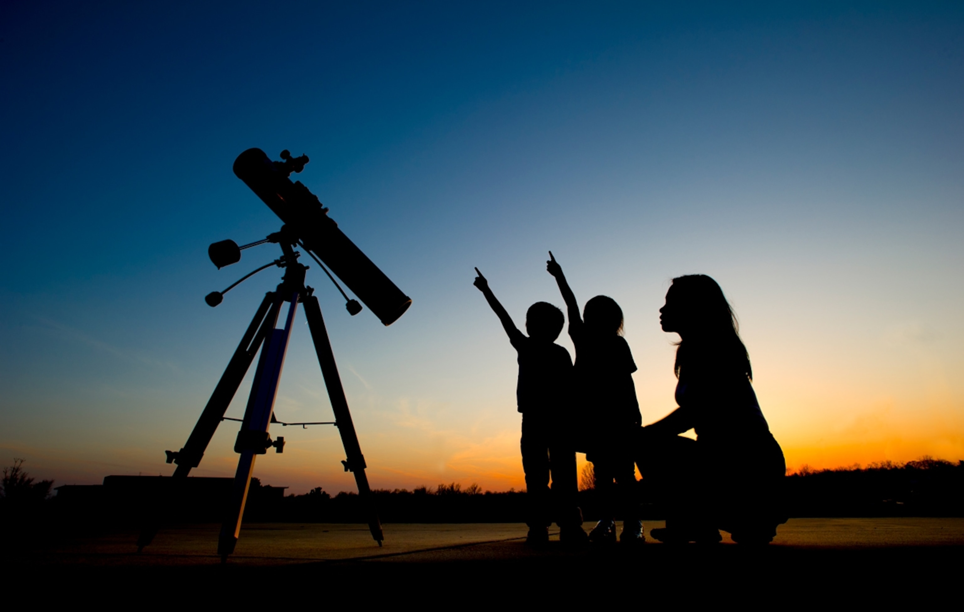 Silhouette of a mother introducing her children to astronomy.