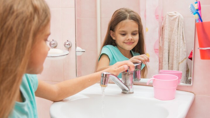 a girl turning off a water faucet