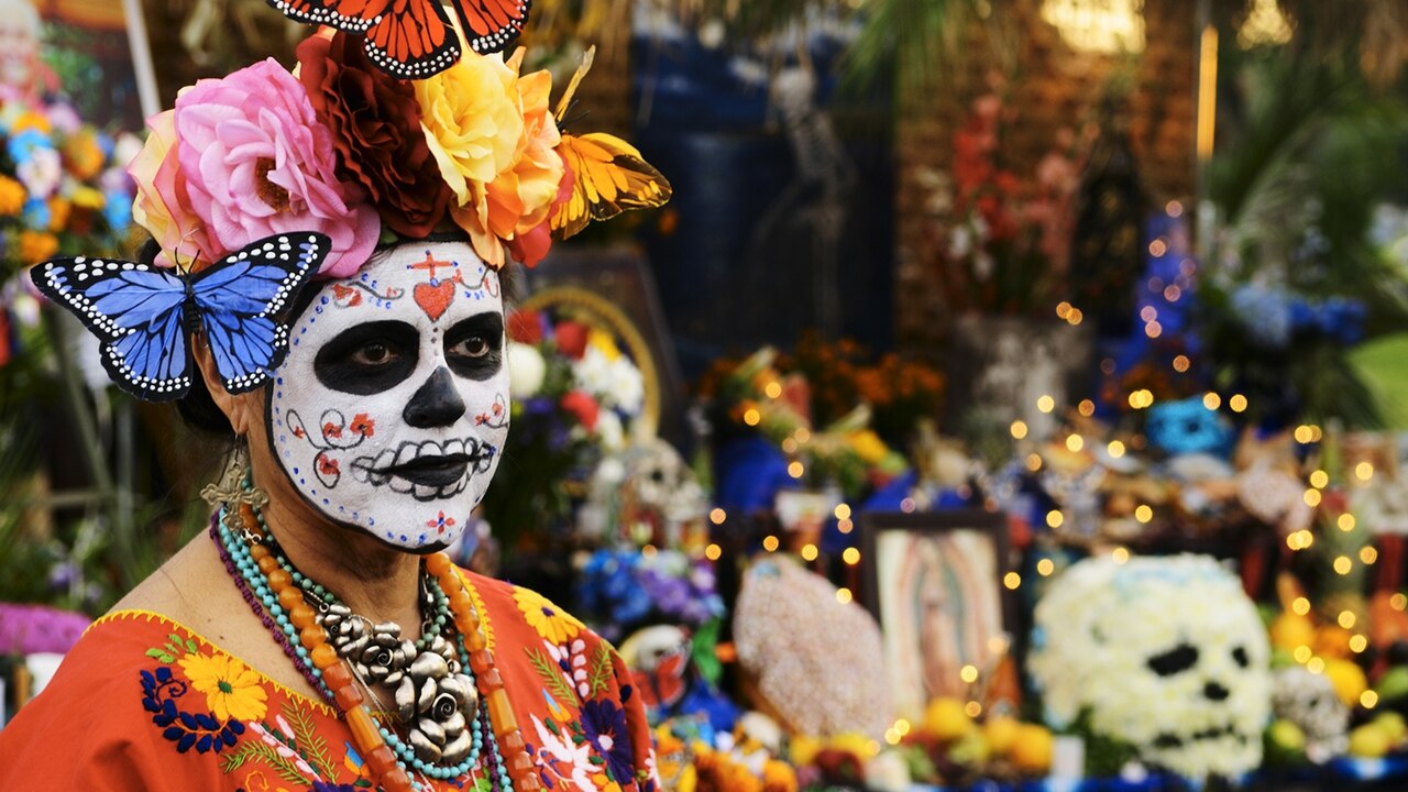 a woman celebrating Day of the Dead with festive face paint.
