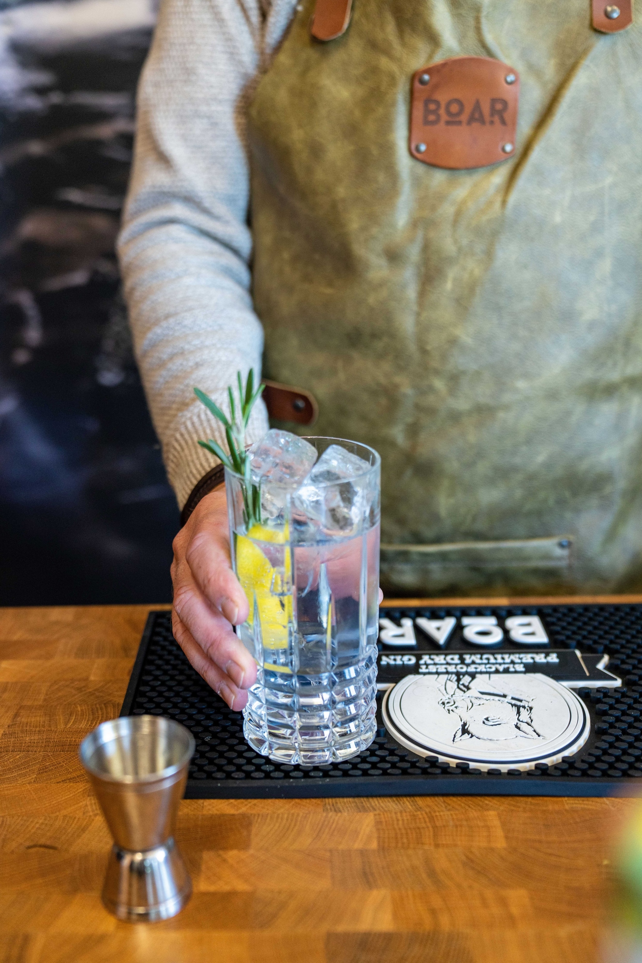 A clear drink with a wedge of lemon poured by a bartender