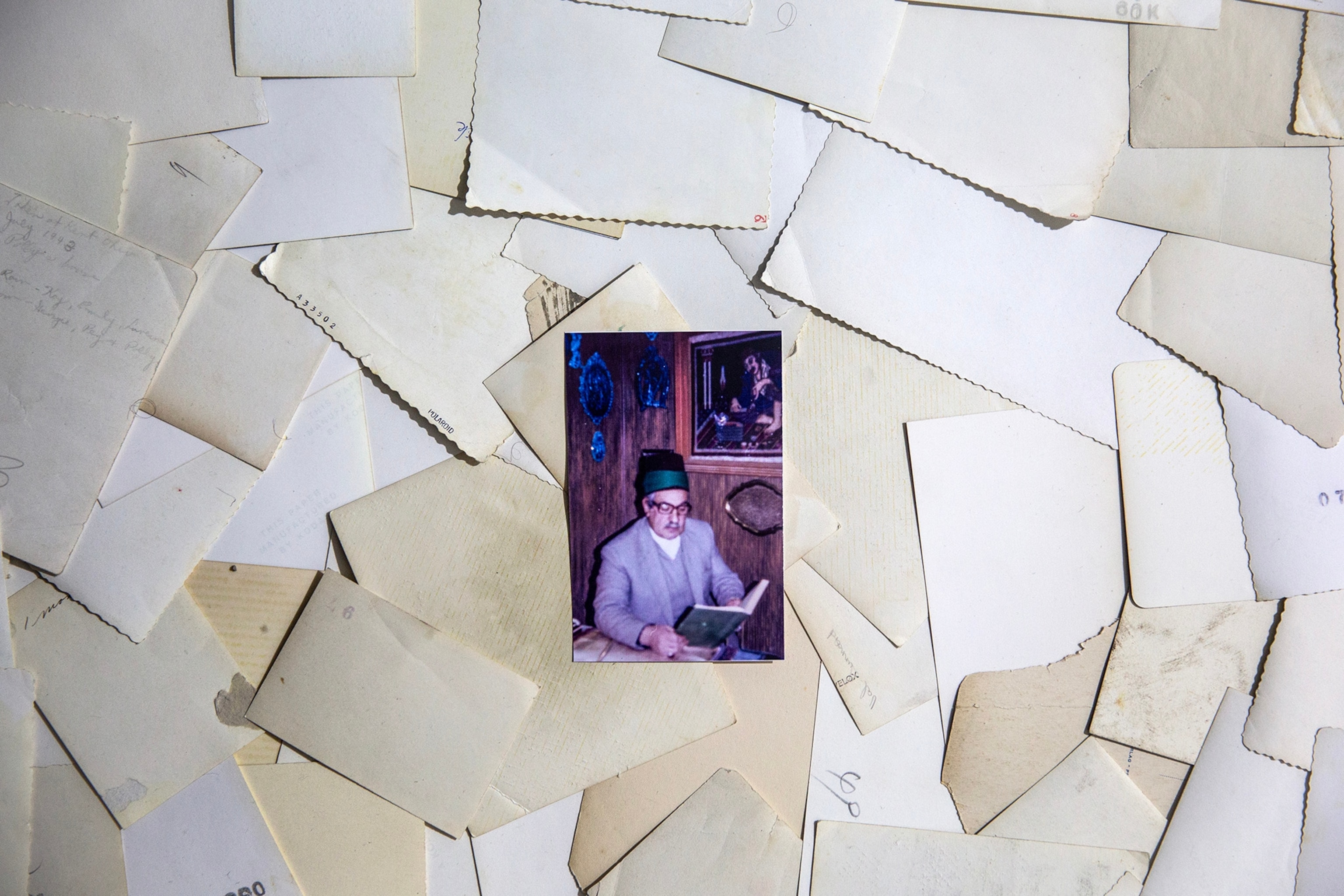 A photo of an elderly man sits face up on a pile of other photographs