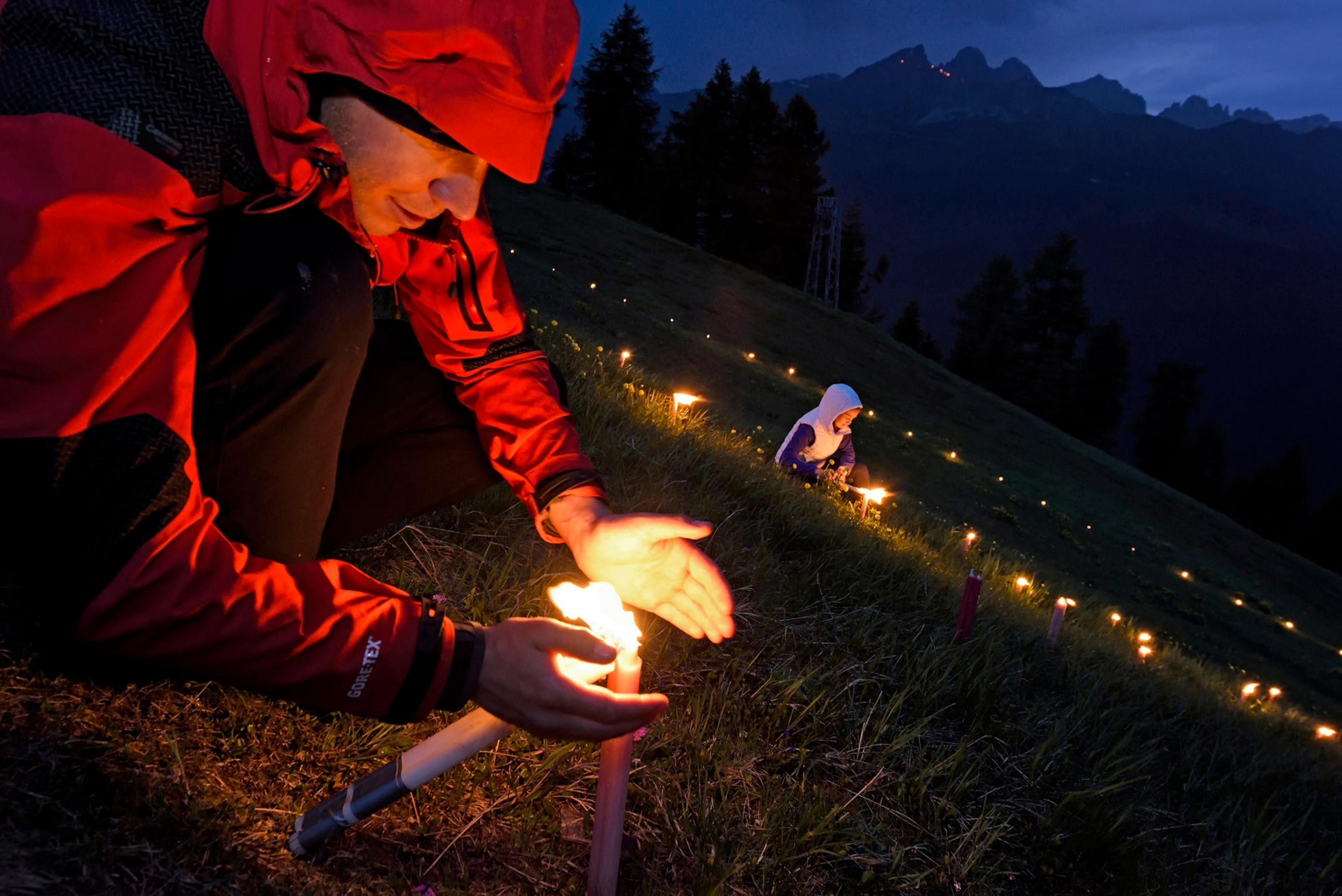a man lighting candles on a mountainside for the Sacred Heart of Jesus celebration
