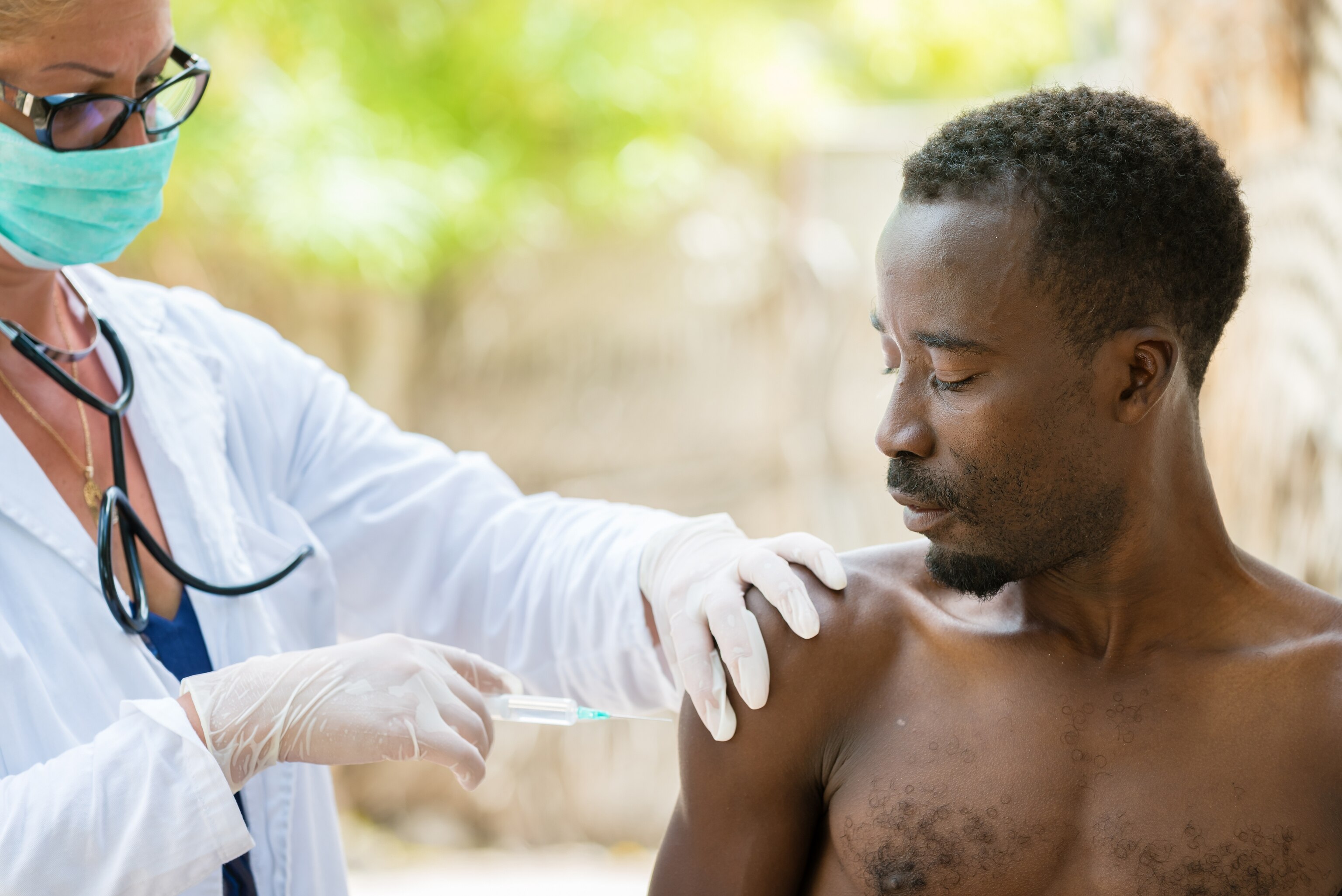 Woman gives a man a vaccination in Africa