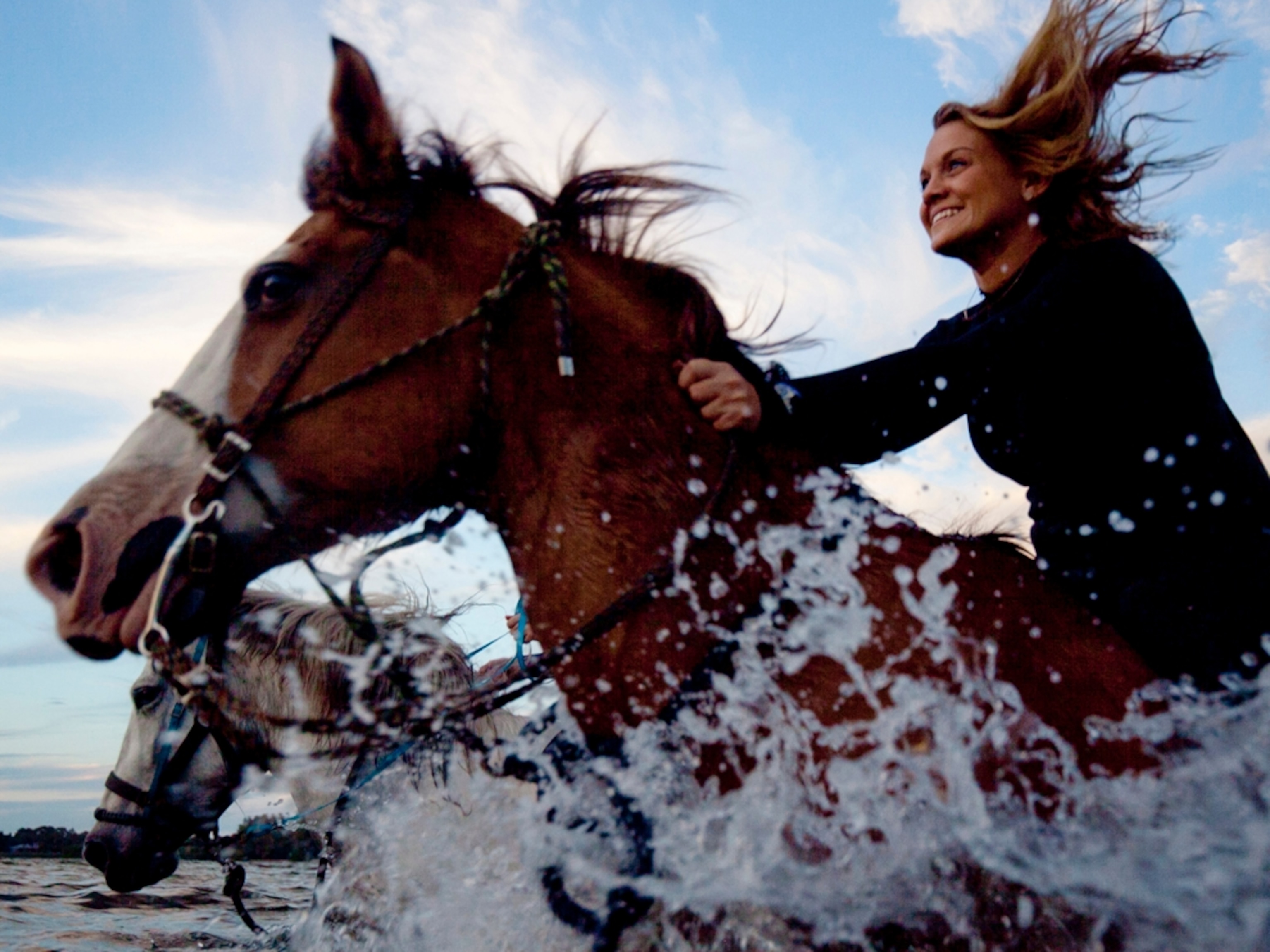 a girl riding a horse through the surf on a Florida beach