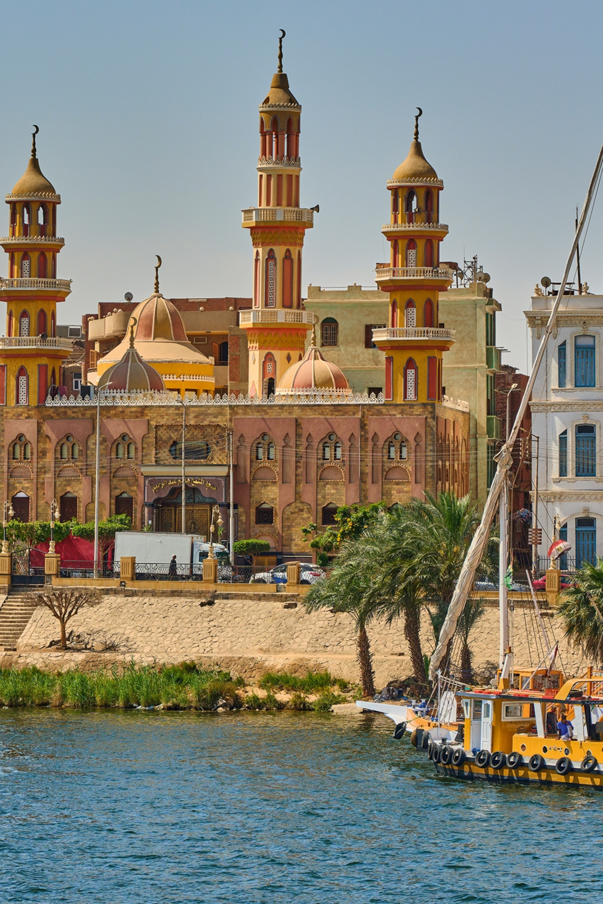 A river front in Egypt with colourful and romantic buildings as well as traditional wooden boats anchored on the shore.