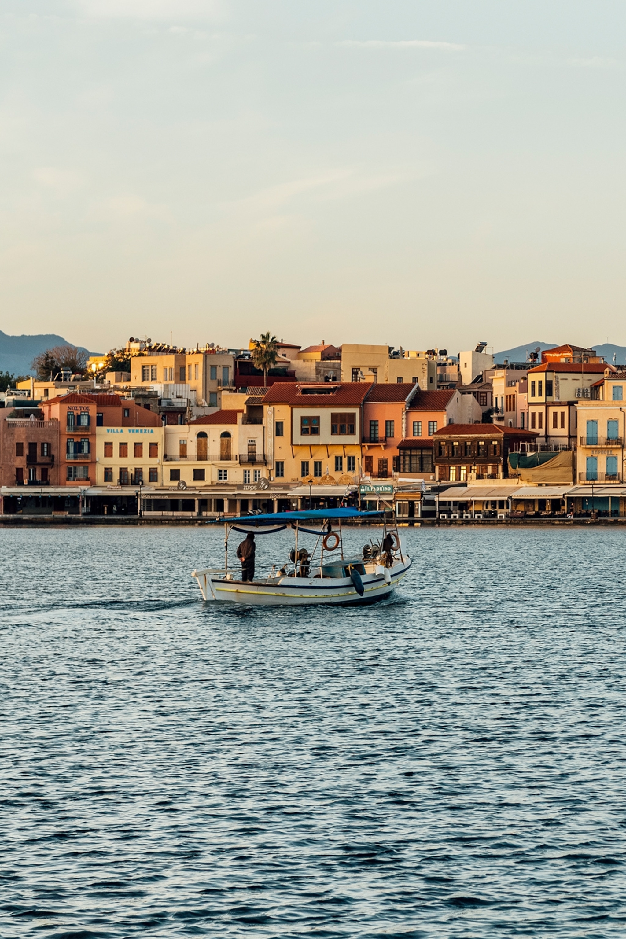 A boat sails by a harbour at dusk.