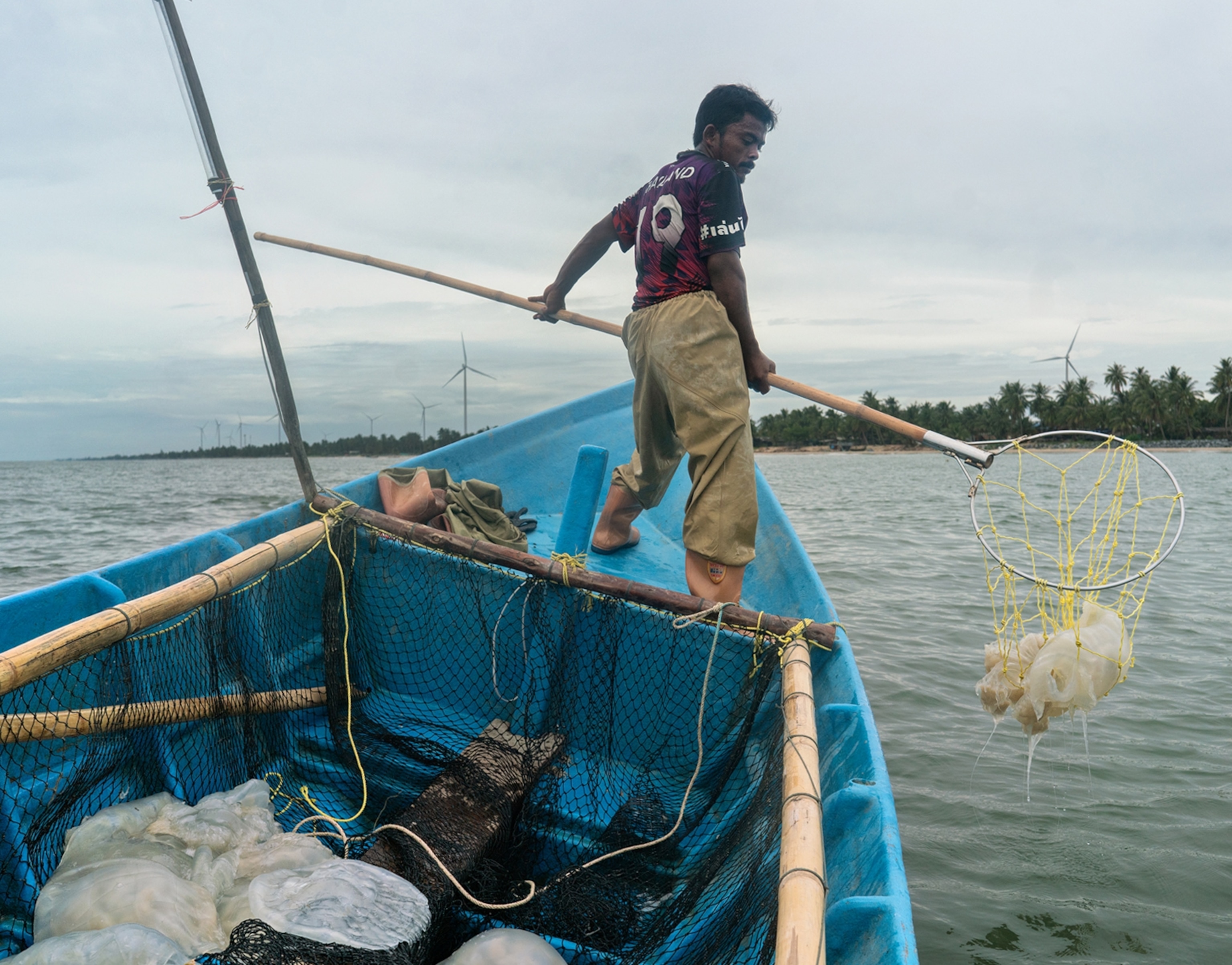 A man stands on a boat with a net