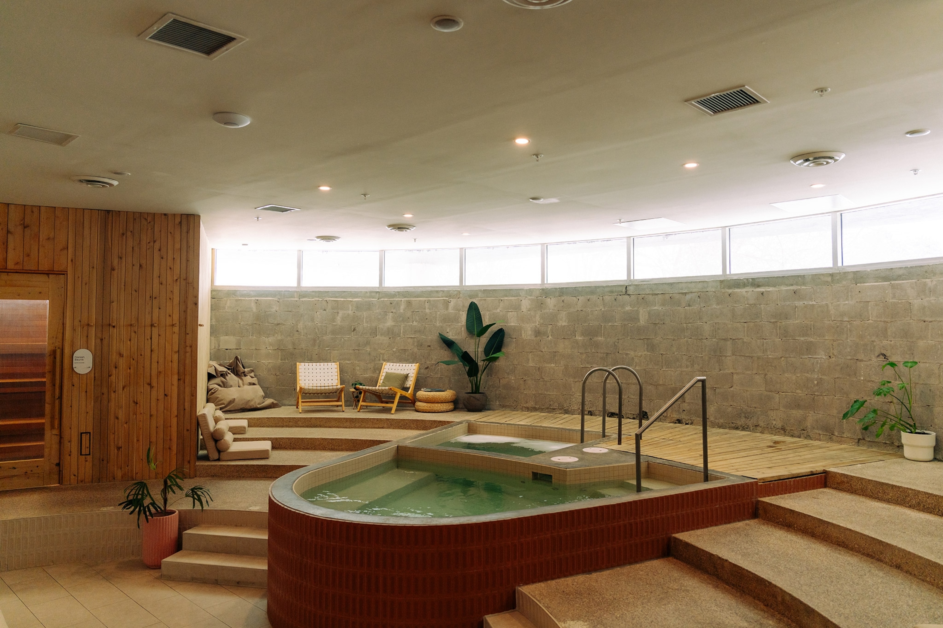 Interior of a modern spa space with small dipping pool, light wood finishings, curved walls