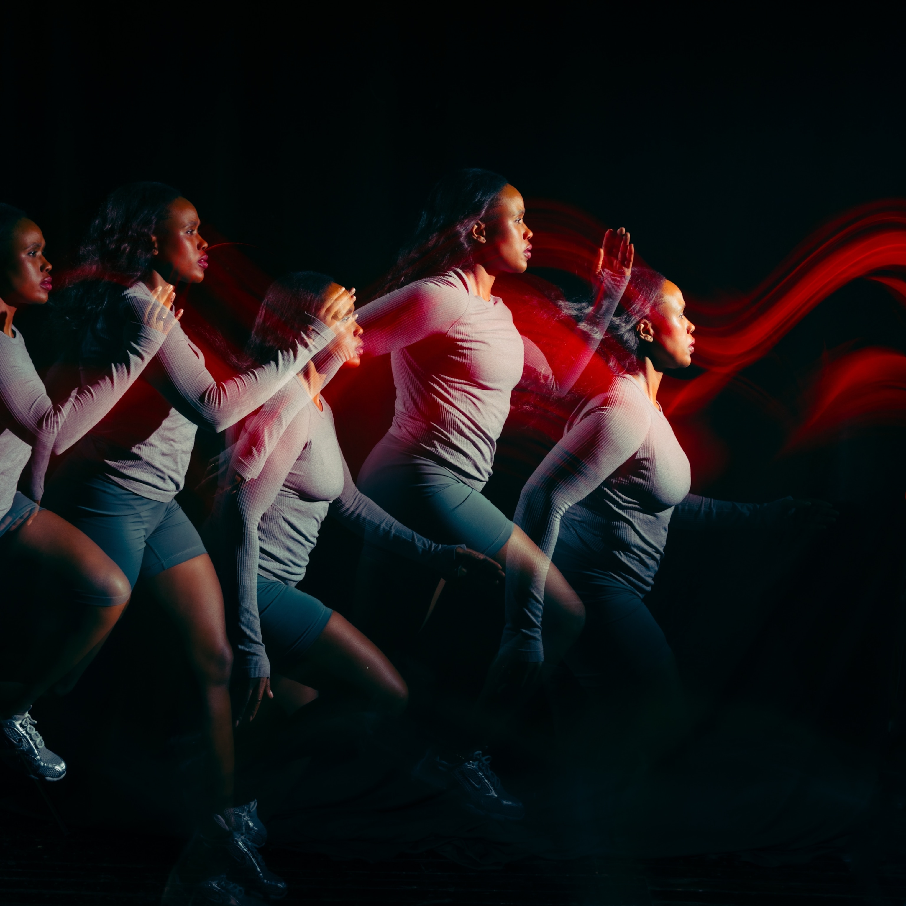 A woman running, her form blurred by the fast motion and a swoosh of red light passes across her head and her core