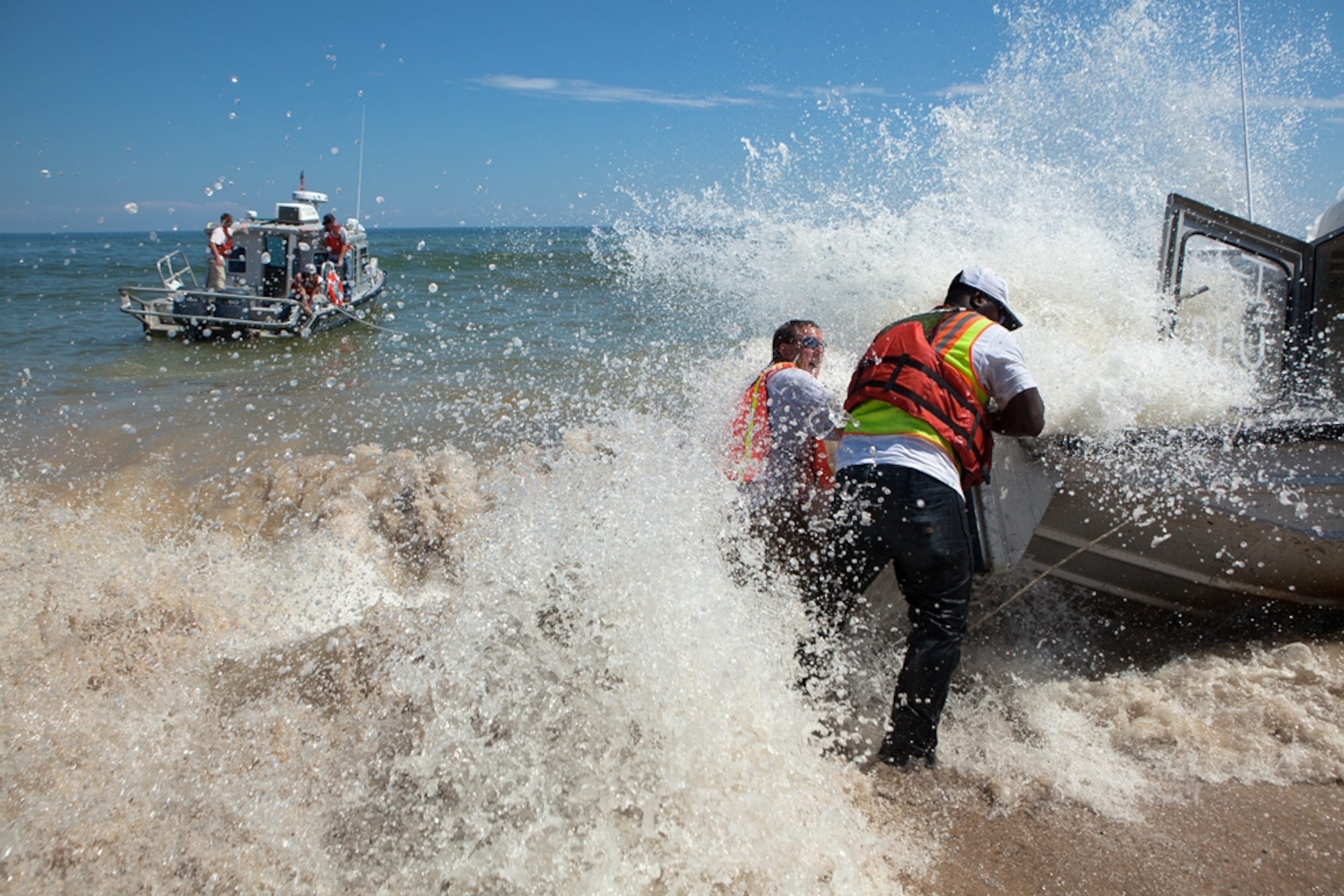 An oil spill cleanup boat is beached by the surf.