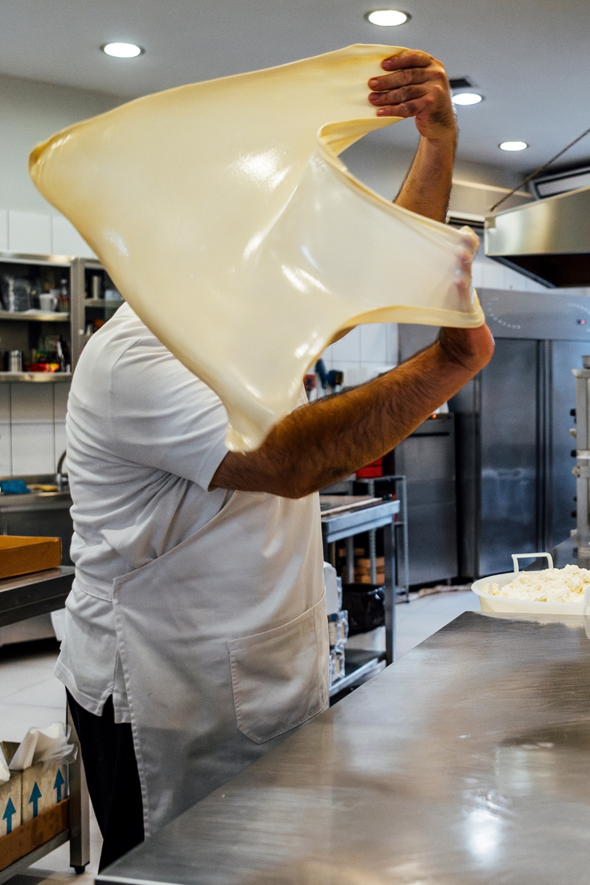 A man stretches pie pastry dough in a swift motion.