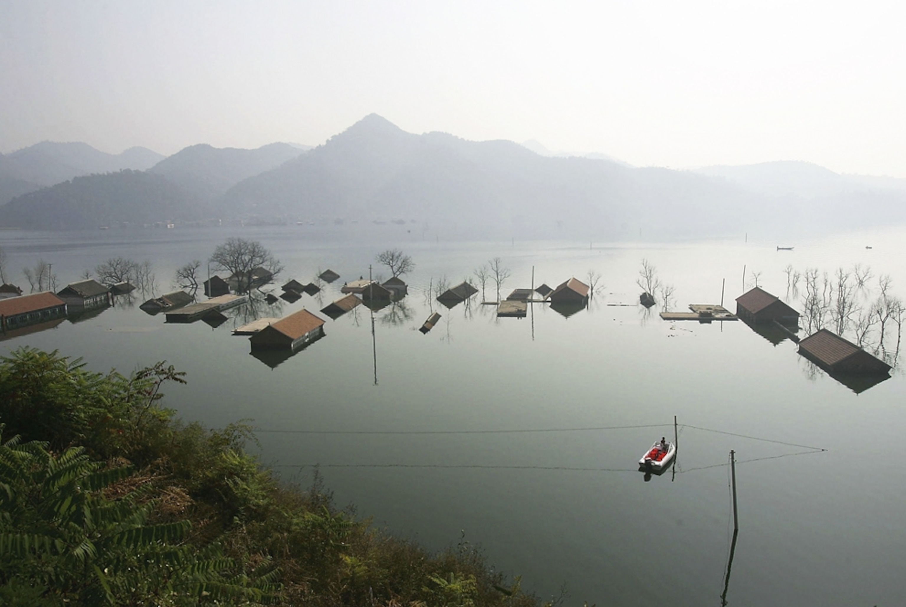 A boat sails beside the roofs of submerged houses