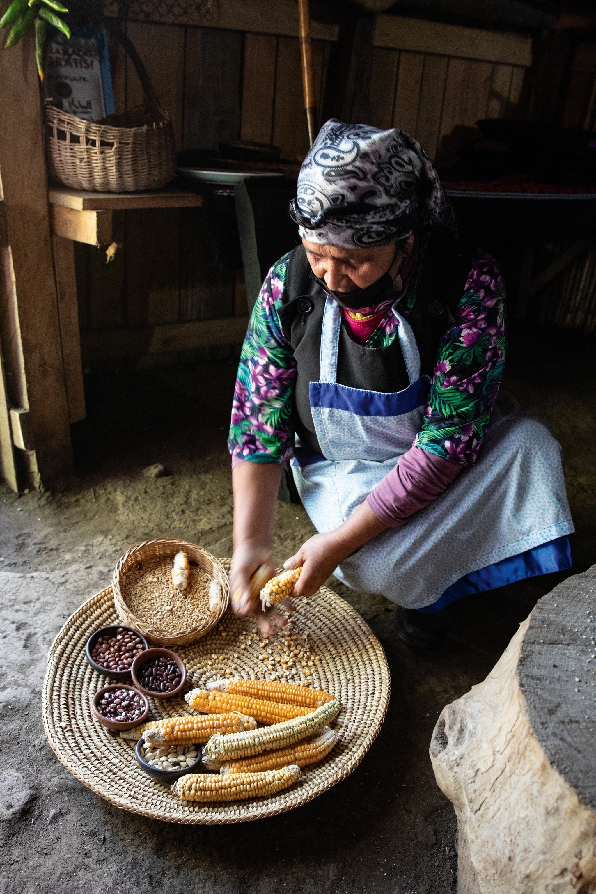 An older woman strips corn for a lunch inside her family home.