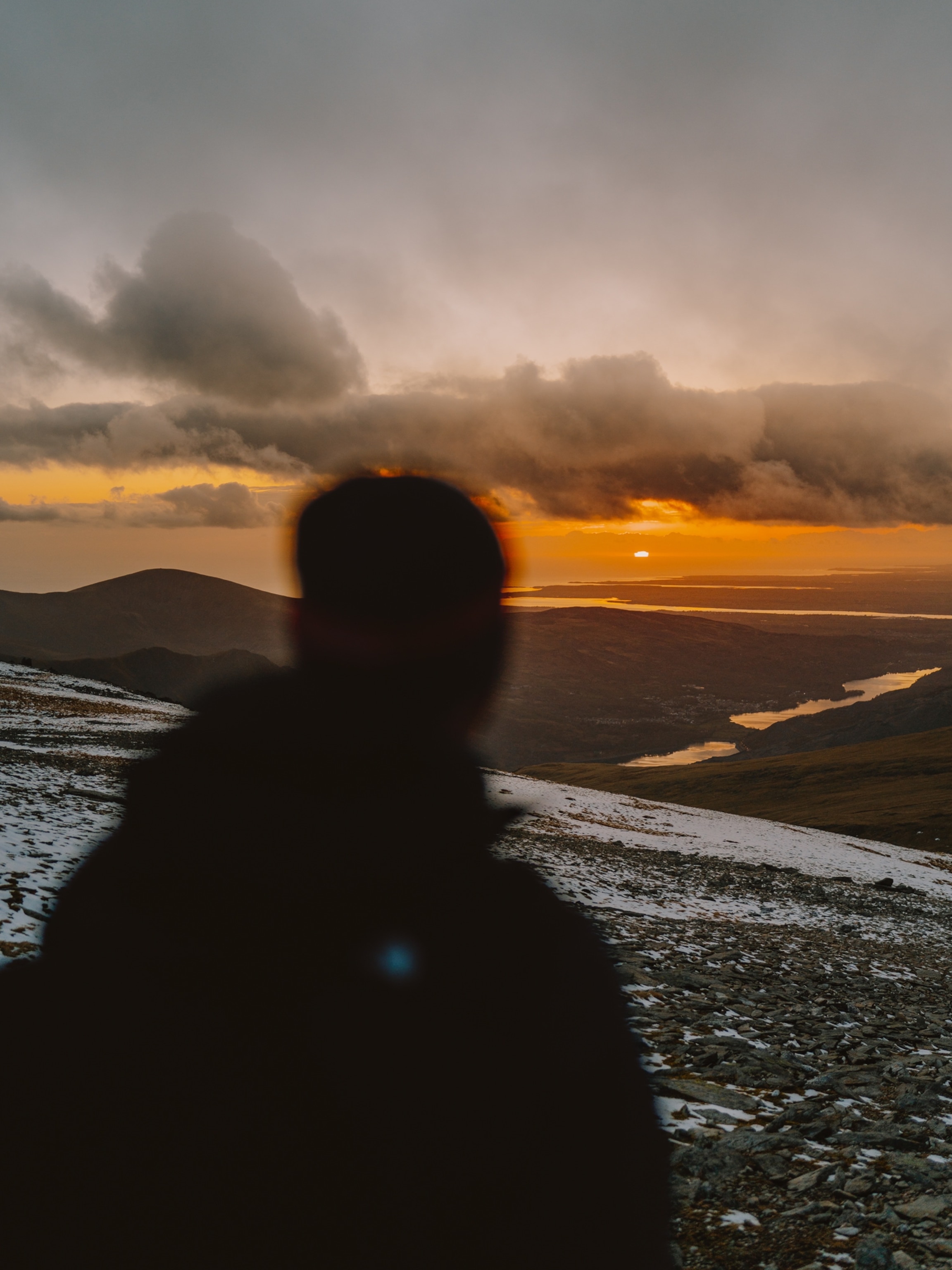 A silhoutte of a person looking at the Glyder Mountains.