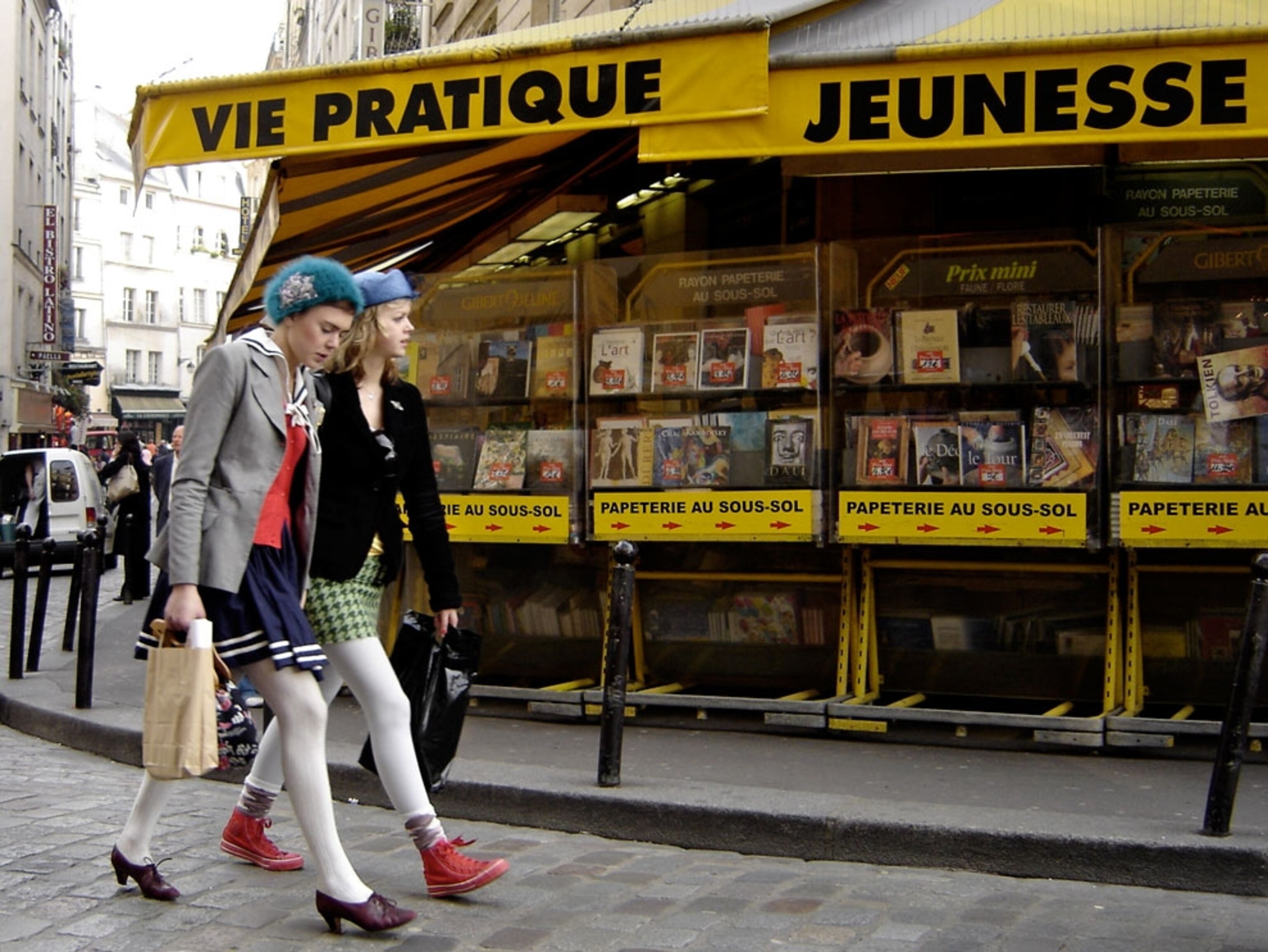 Girls walking by a newsstand