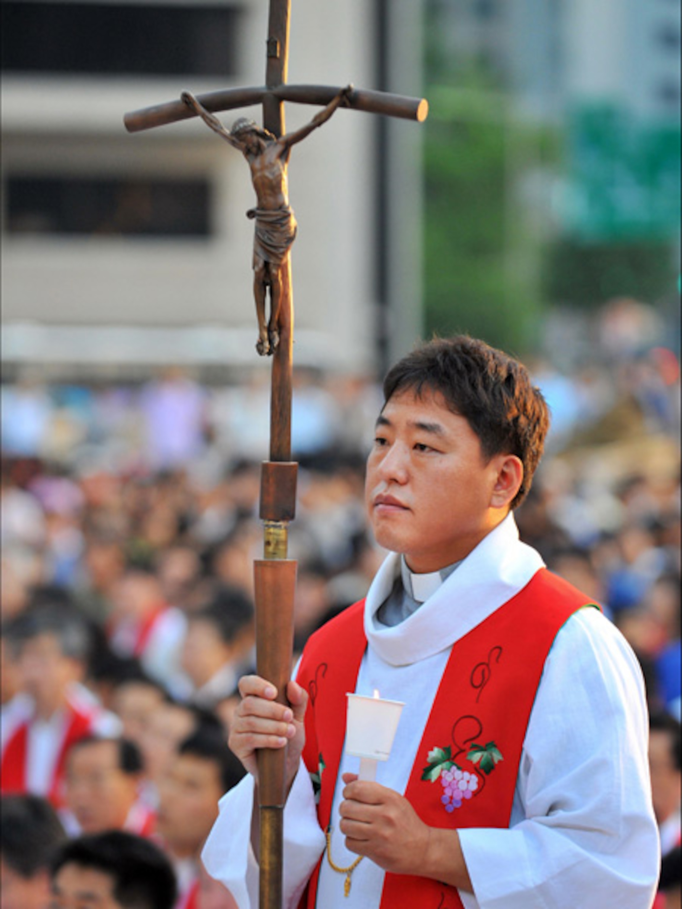 A Korean pastor holding a cross and a candle