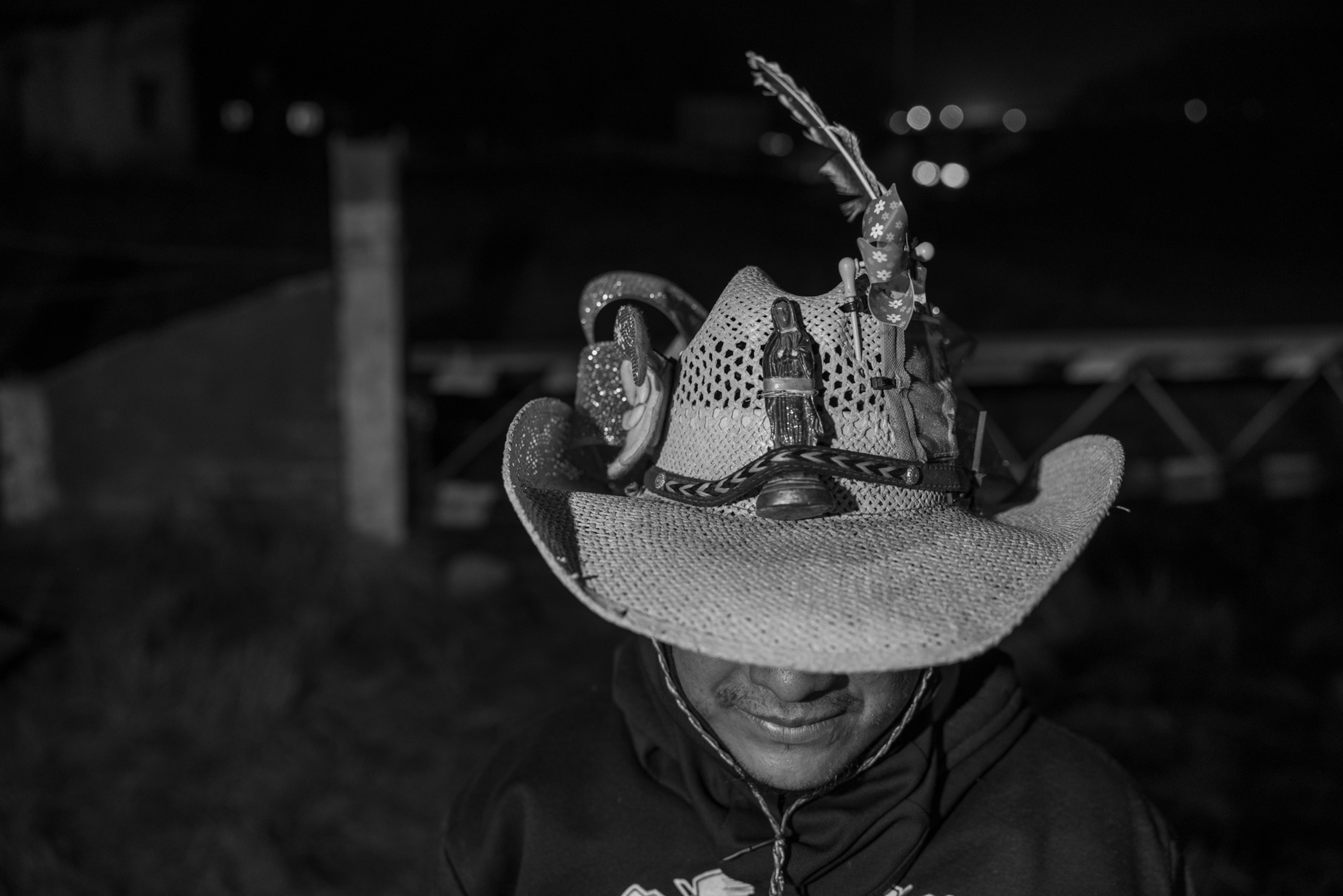 A close up of a persons hat that has statues of a woman praying attached to it.