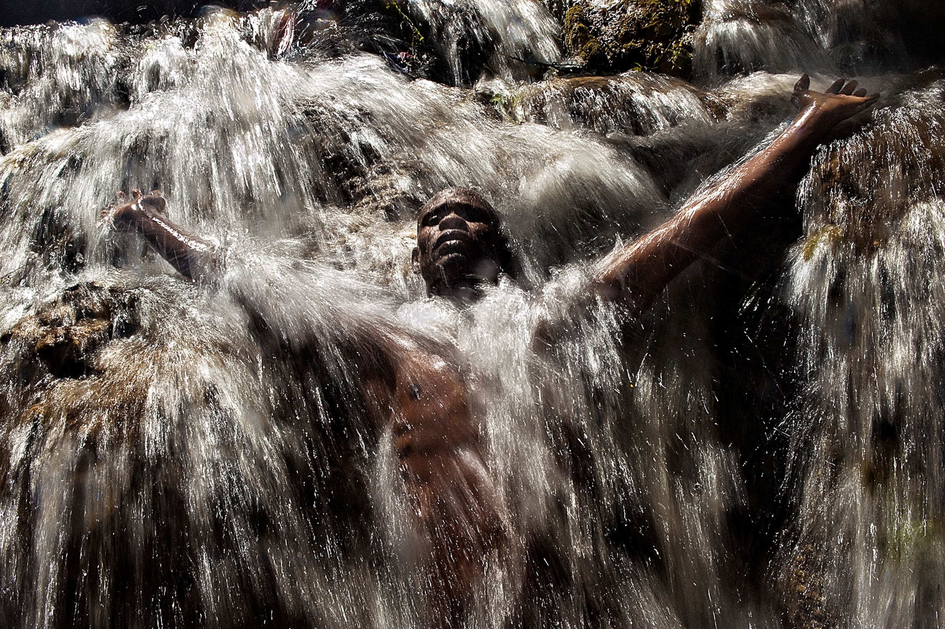 a man underneath a waterfall in Saut d'Eau, Haiti