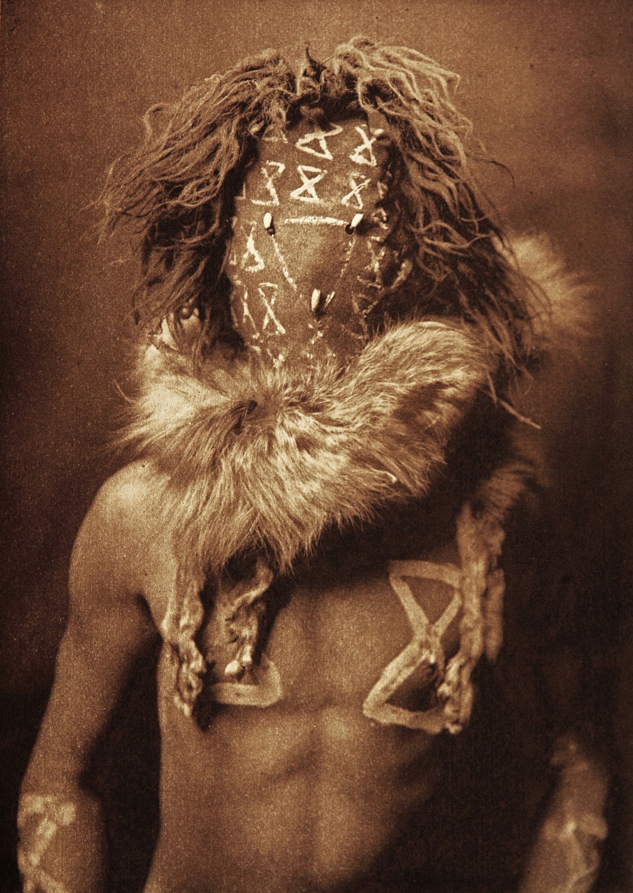 one person of Native American ethnicity in ceremonial costume with obscured face.