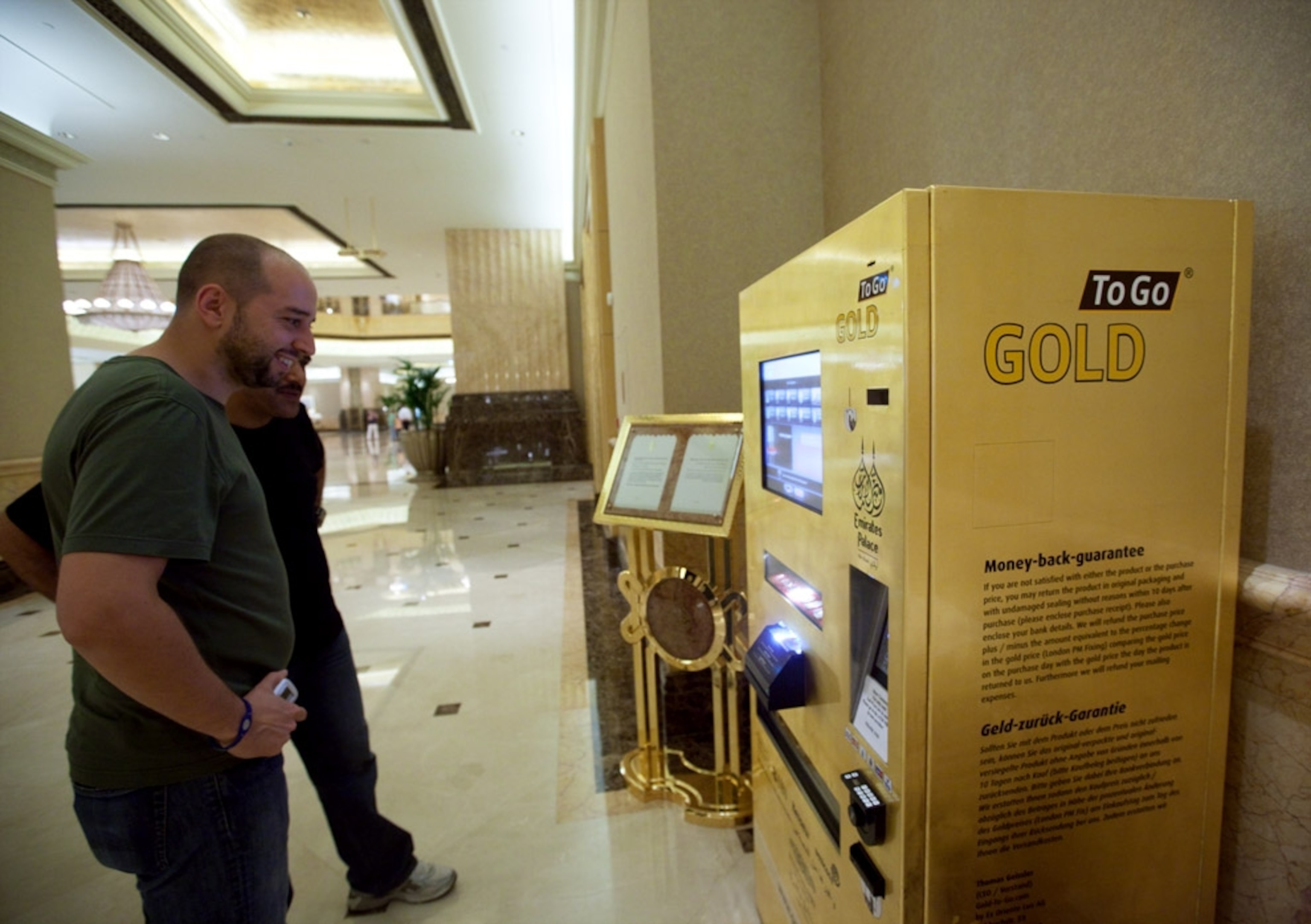 Hotel visitors looking at vending machine that sells gold (photo)