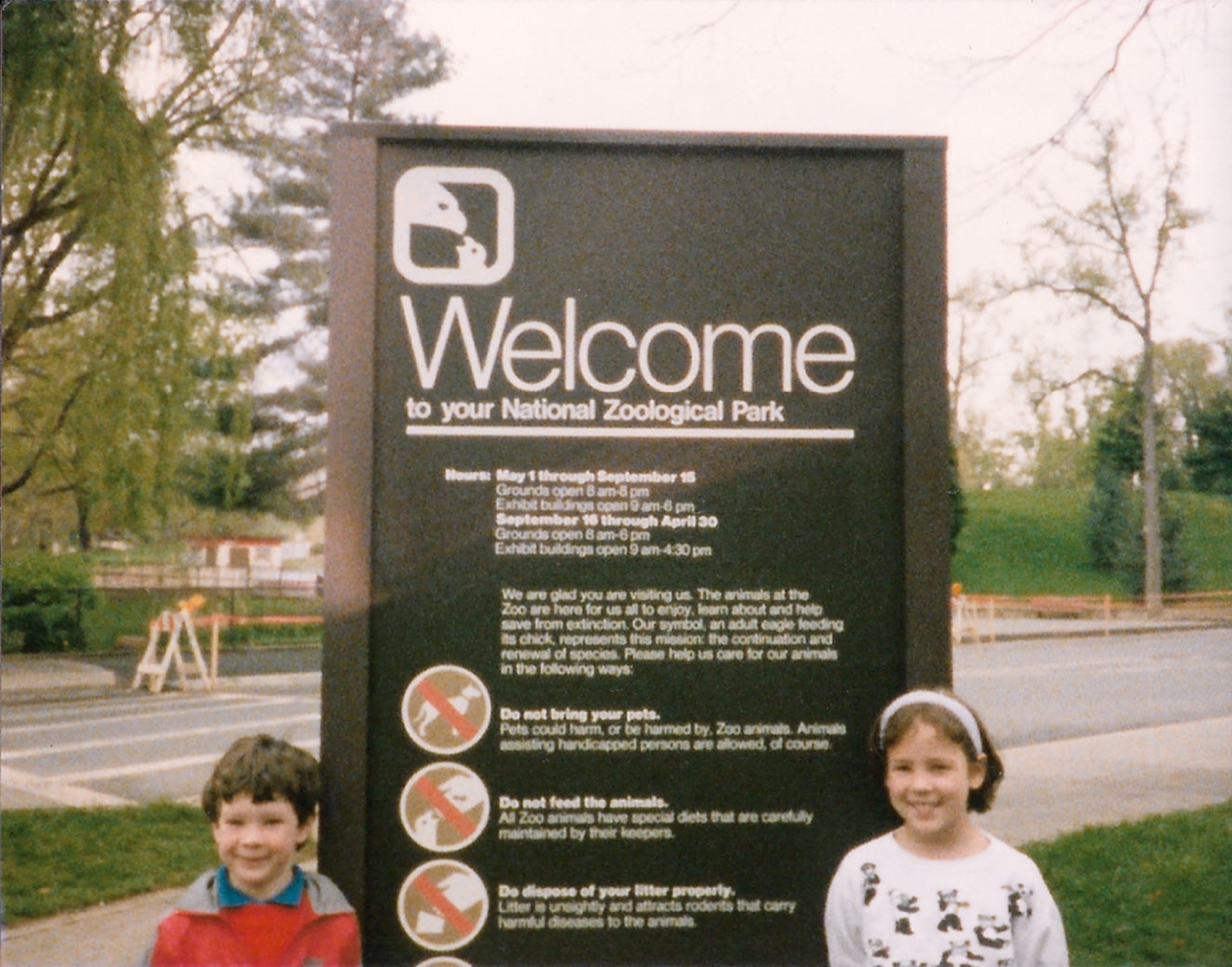 little girl and boy by Welcome Zoo sign.