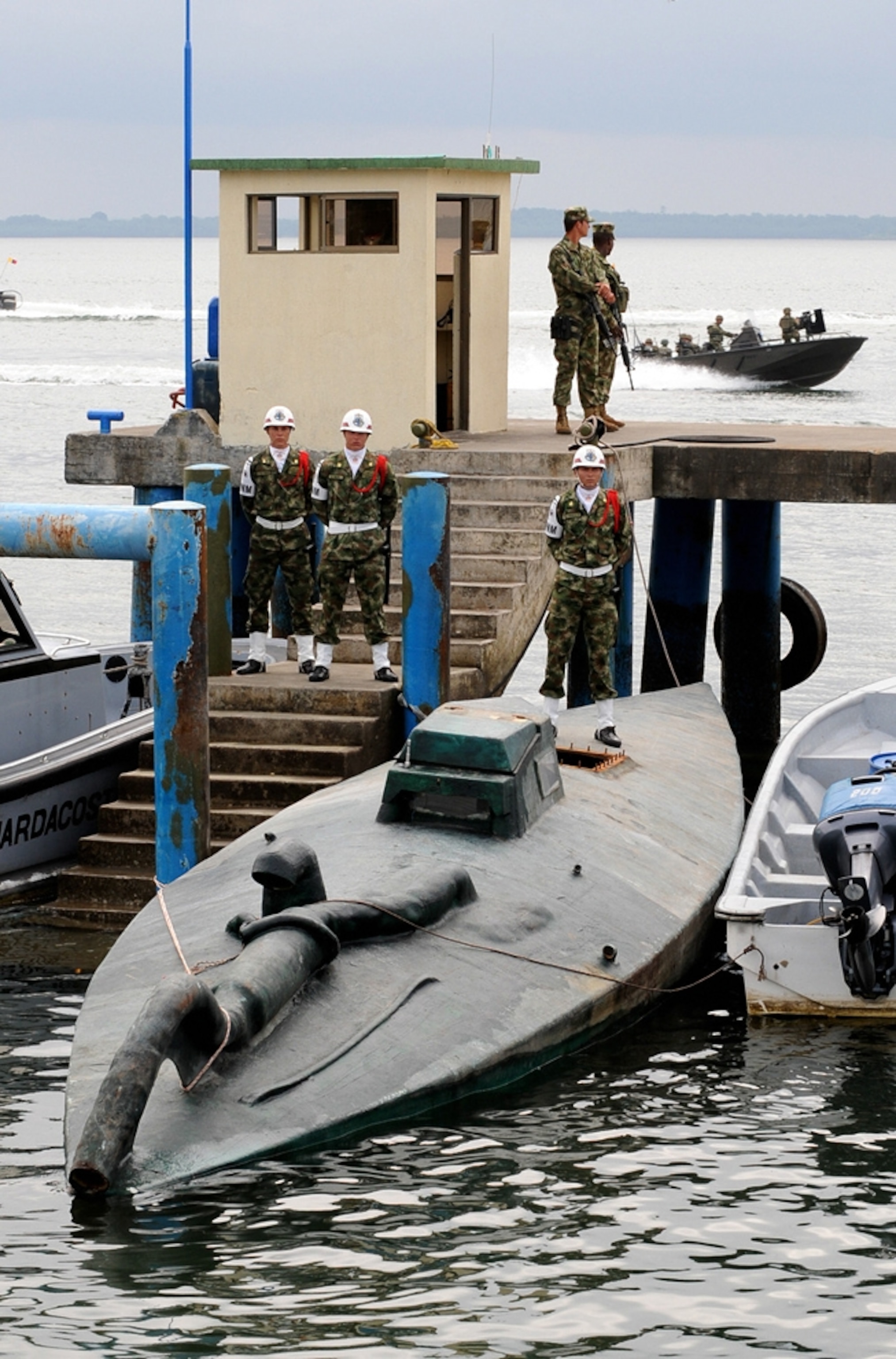Colombian Navy soldiers guarding a homemade cocaine submarine tied to a pier