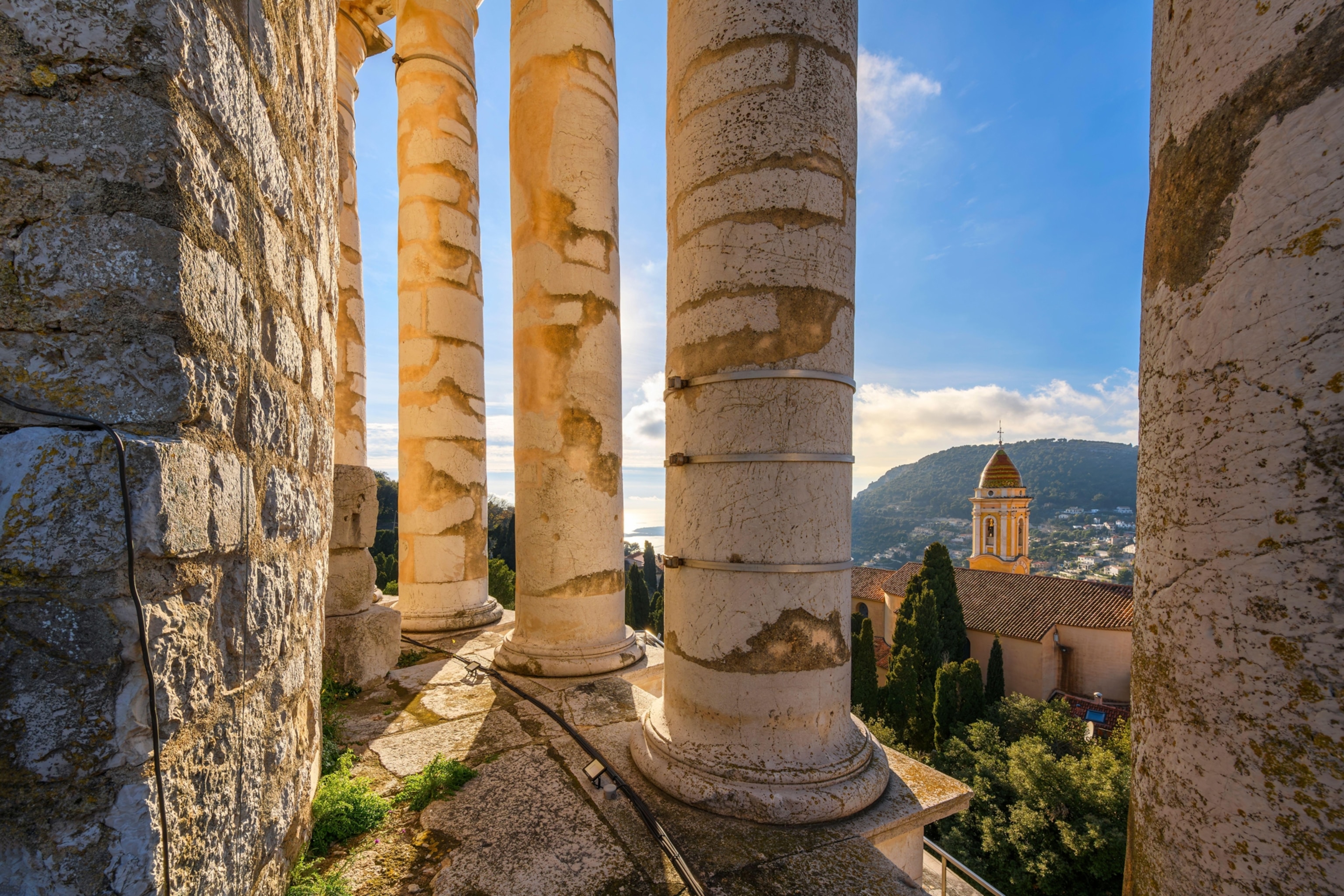 View from inside the columns at the top of the ancient Roman Trophy of Augustus monument of the Mediterranean Sea and church of La Turbie, France.