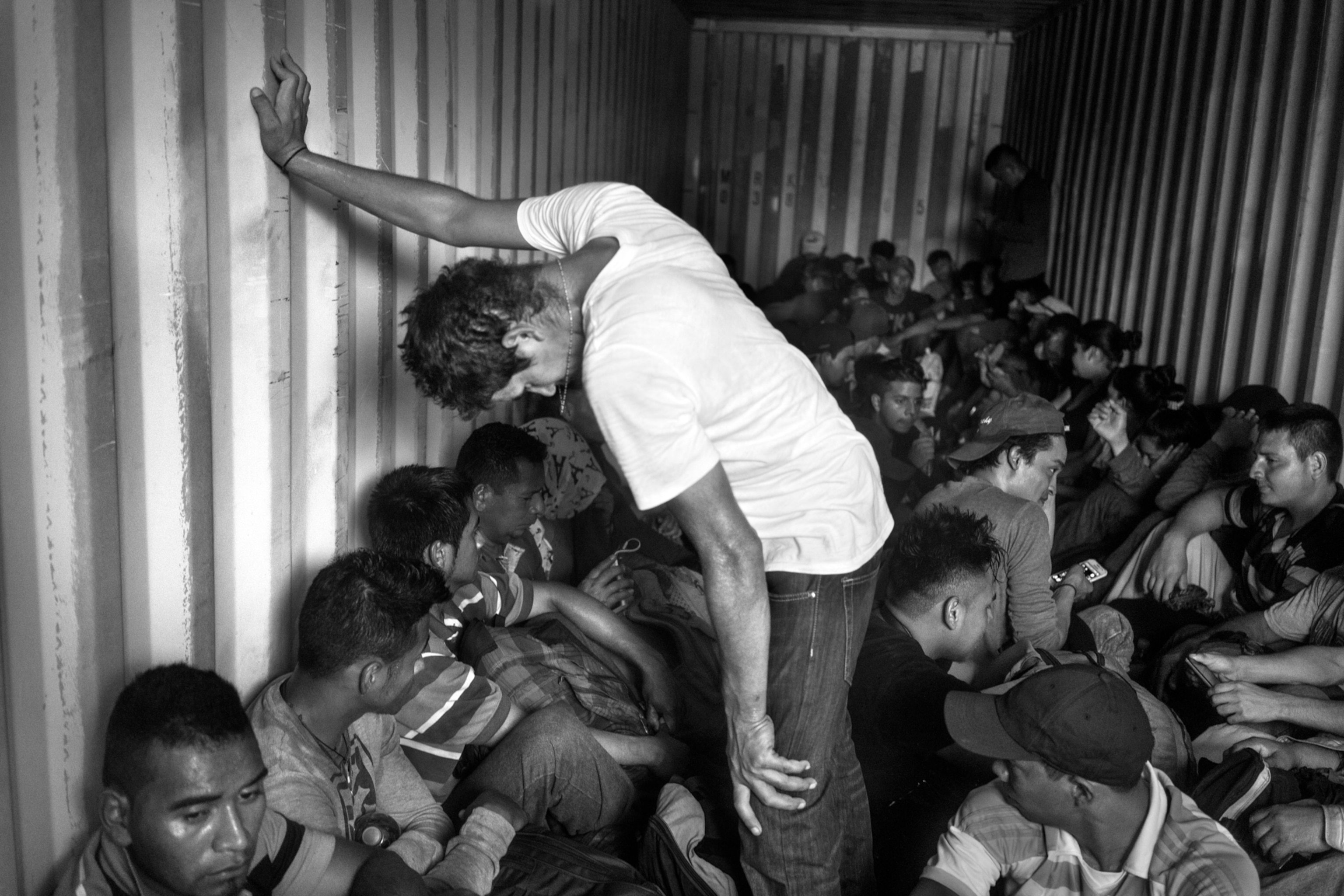 men in a container and a man in white leaning against the container