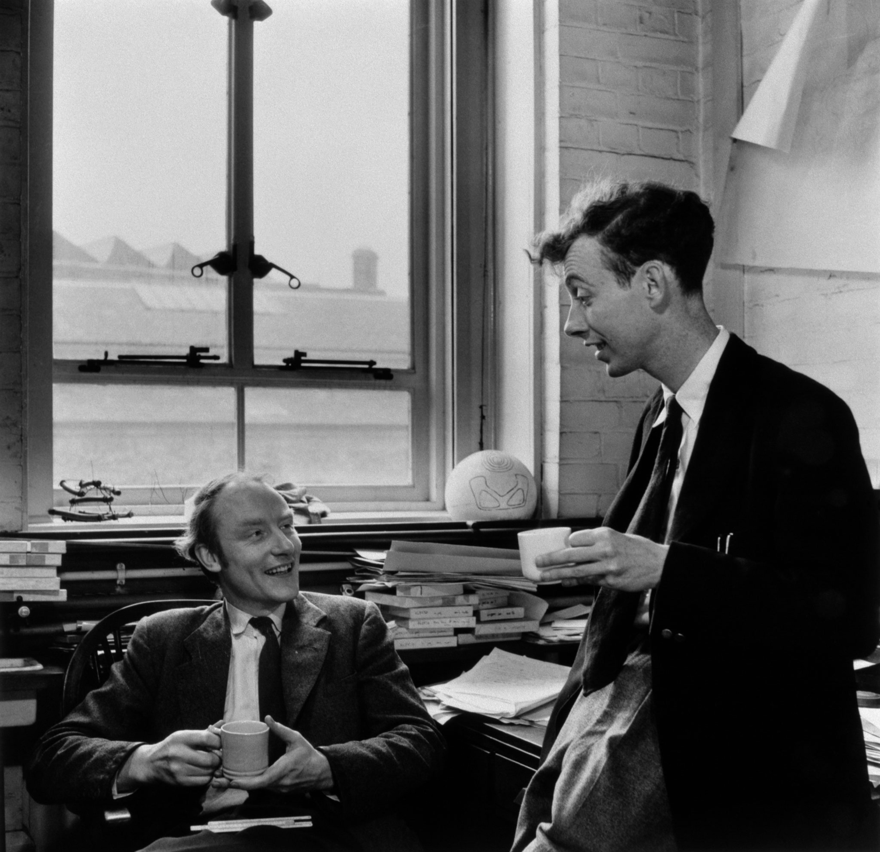 In a black and white archival image, James Watson and Francis Crick talk in the library.