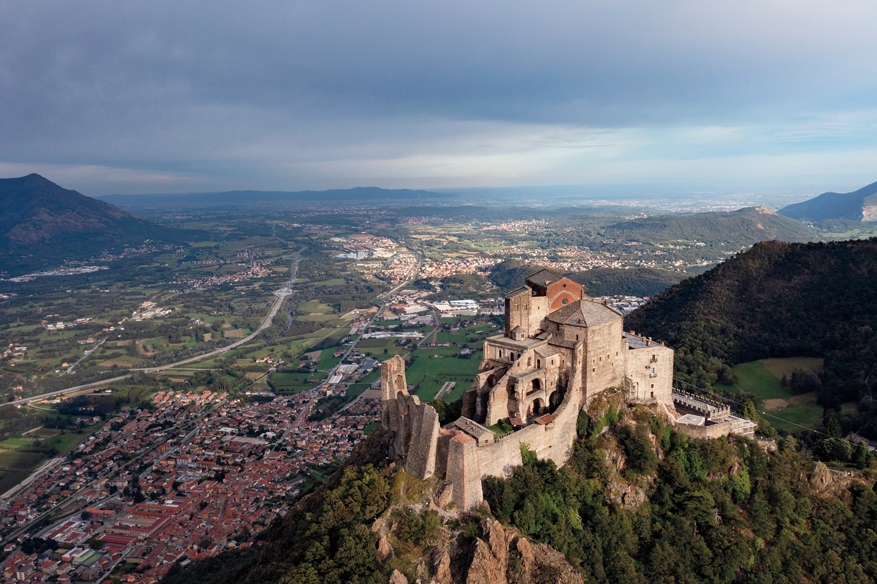 An wide overhead view of a monastery on the top of a mountain, looking over the town below.