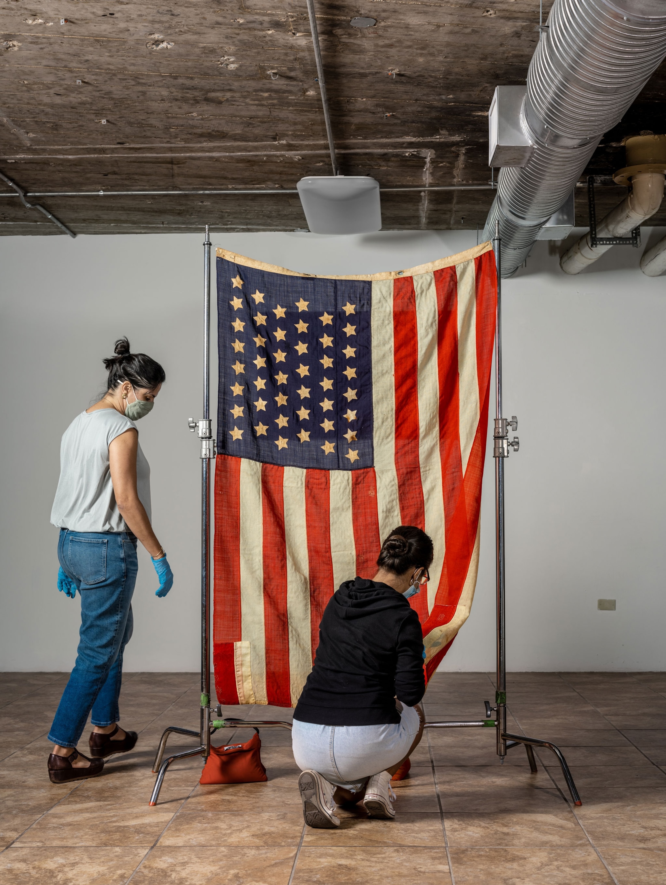 Two women mending the old flag.