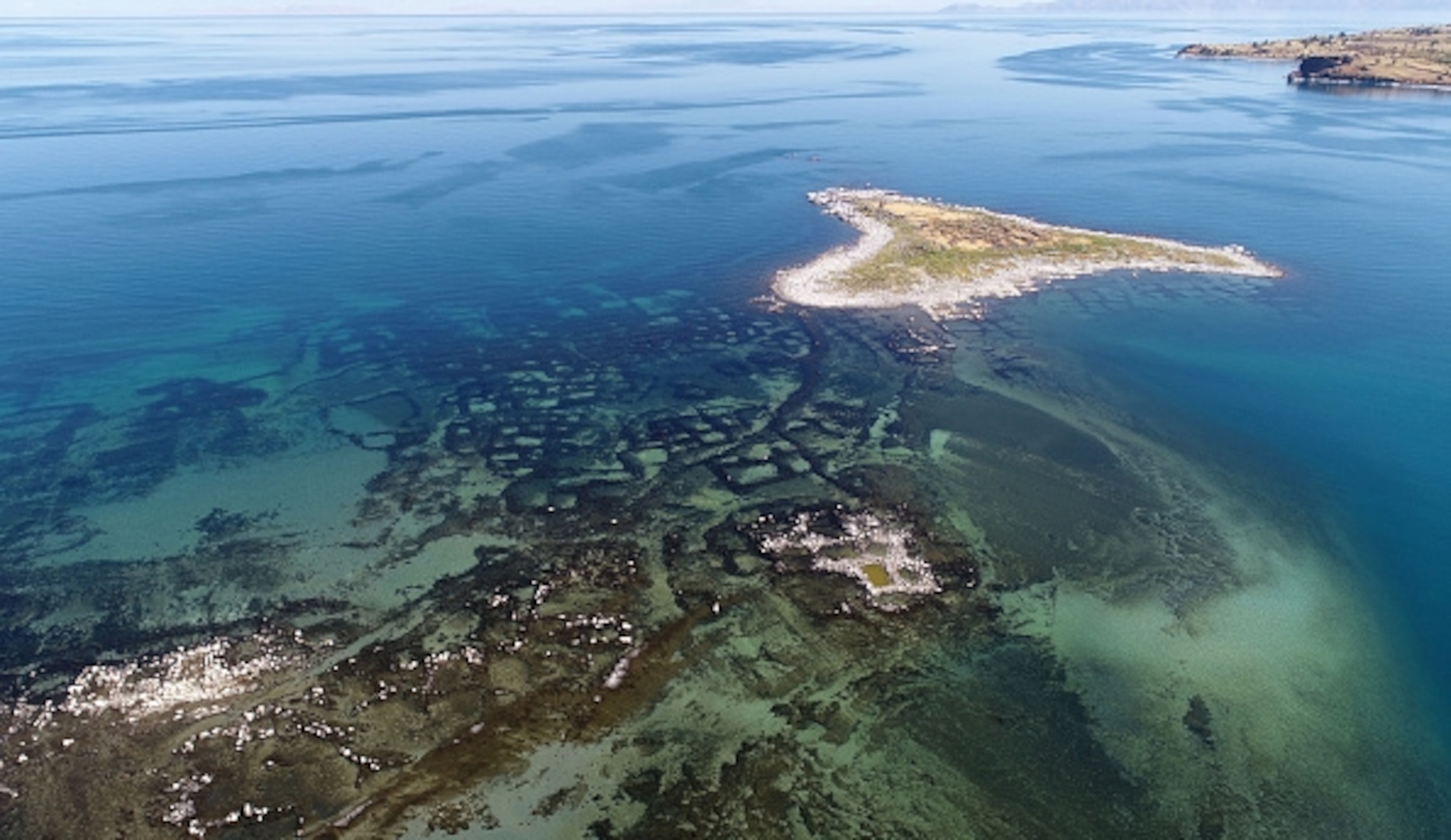 An aerial view of the area as the water recedes previously submerged structures and graves have emerged, and small islands have become visible.