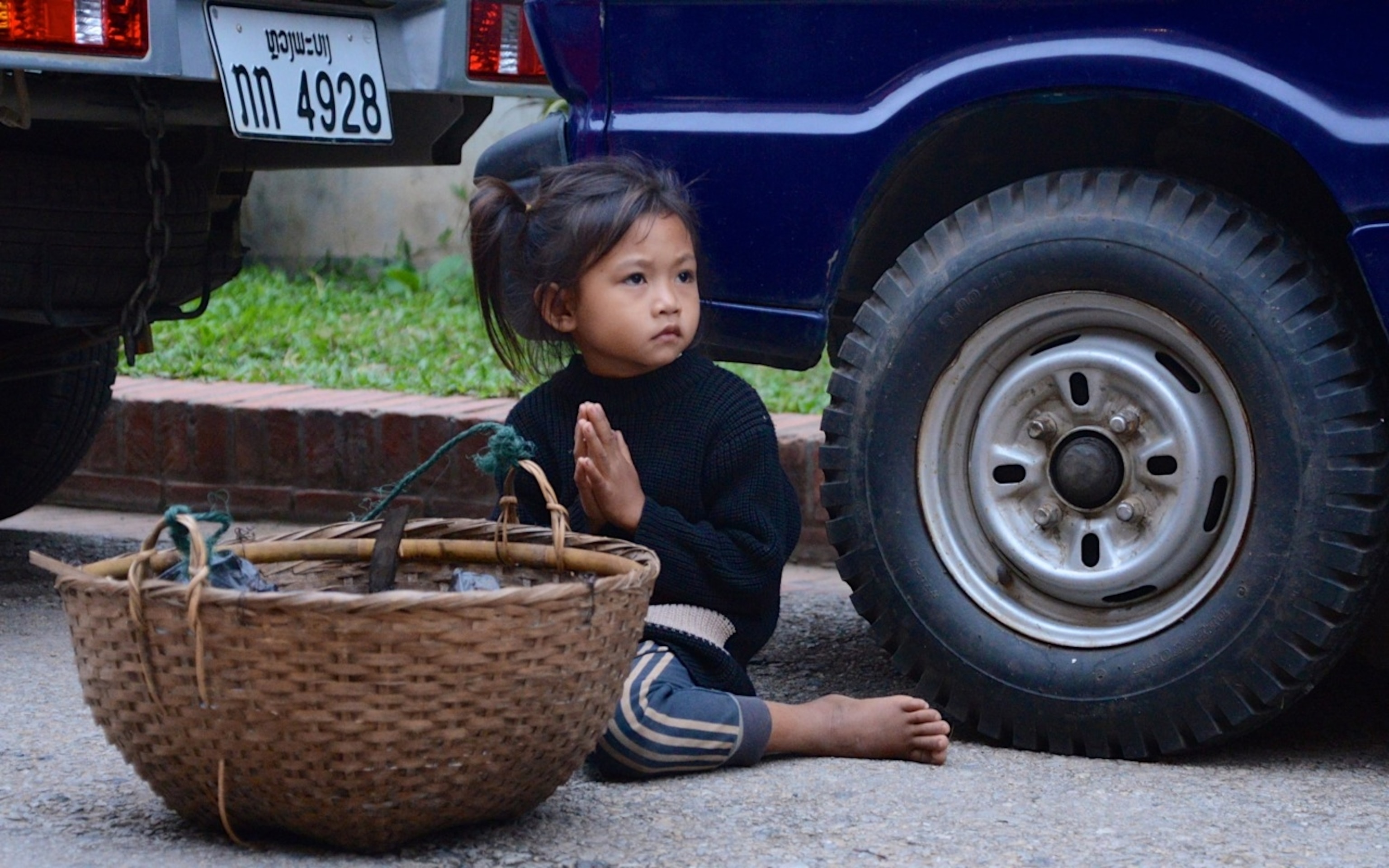 A little girl waits for alms from the passing Buddhist monks in Luang Prabang, Laos. (By Andrew Evans, National Geographic)