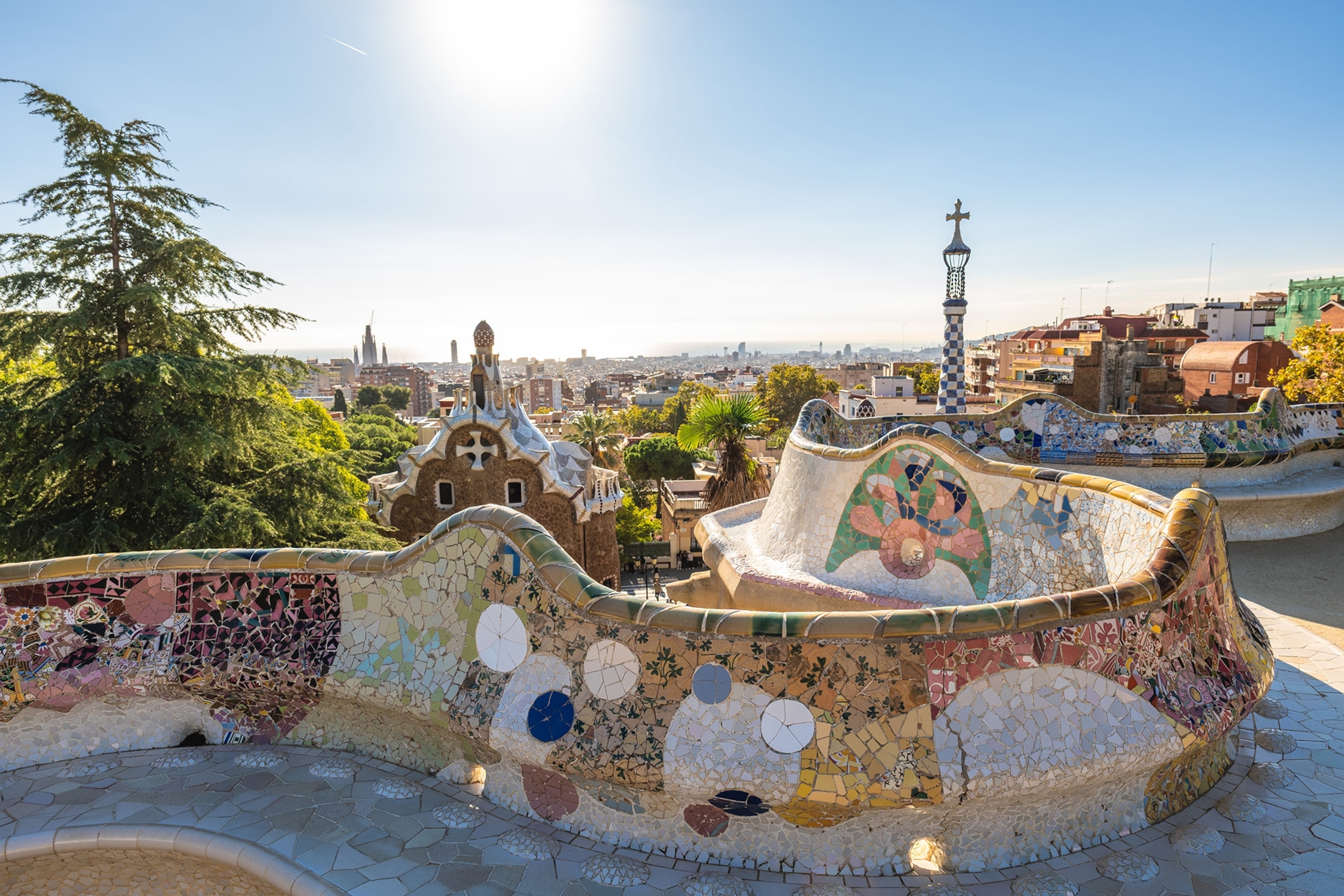 A curved bench decorated with tiles in a mosaic pattern overlooks the city of Barcelona.