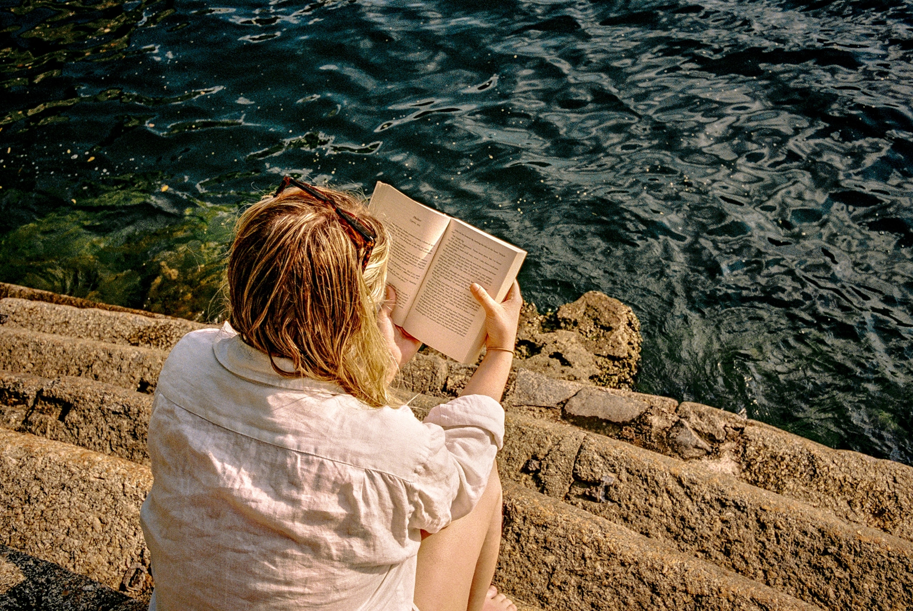 Rear view of woman reading book on steps near Lake Como, Nesso, Como, Italy