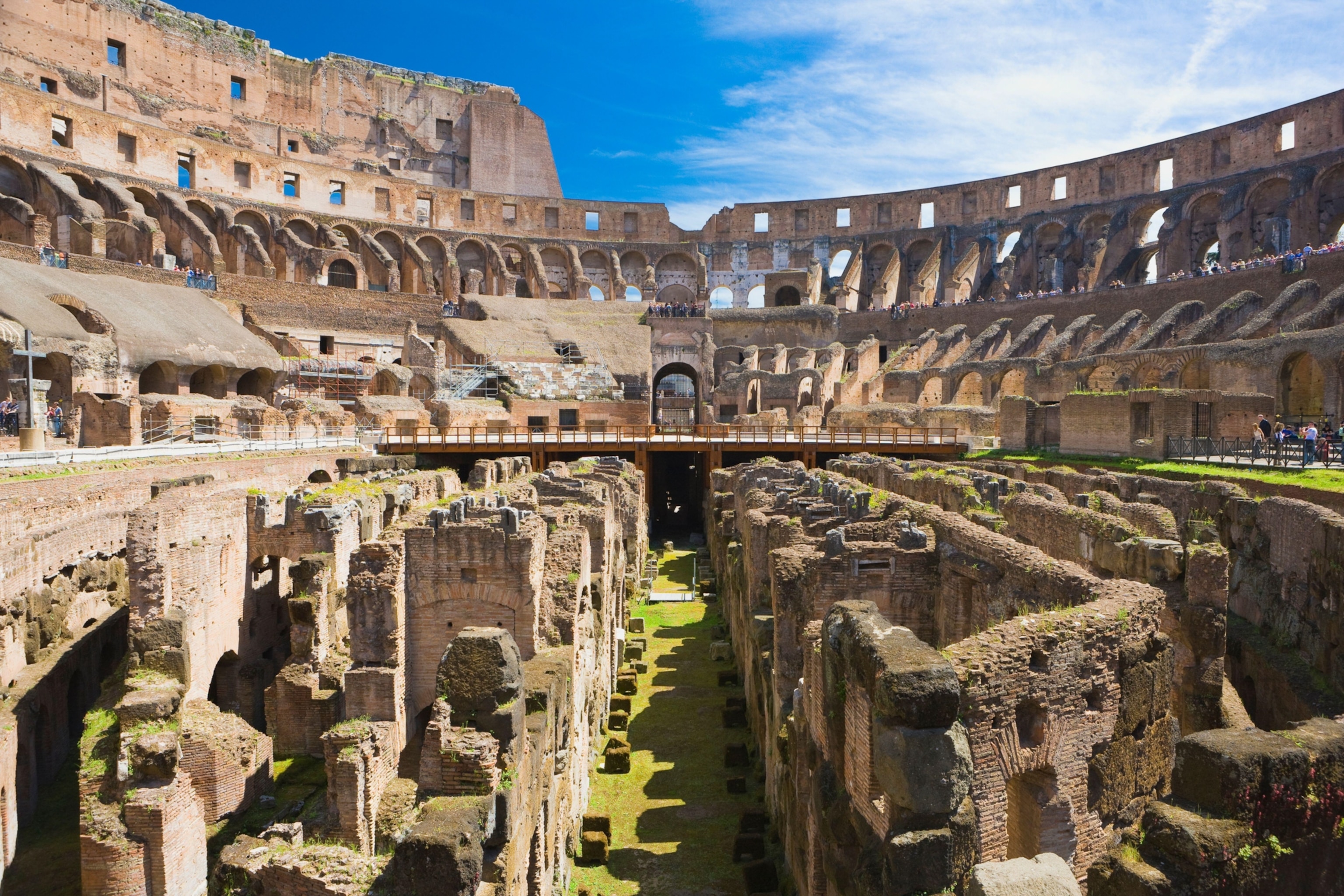 The interior of the Colosseum reveals ancient underground chambers, stone passageways, and tiers of arches beneath the historic arena.