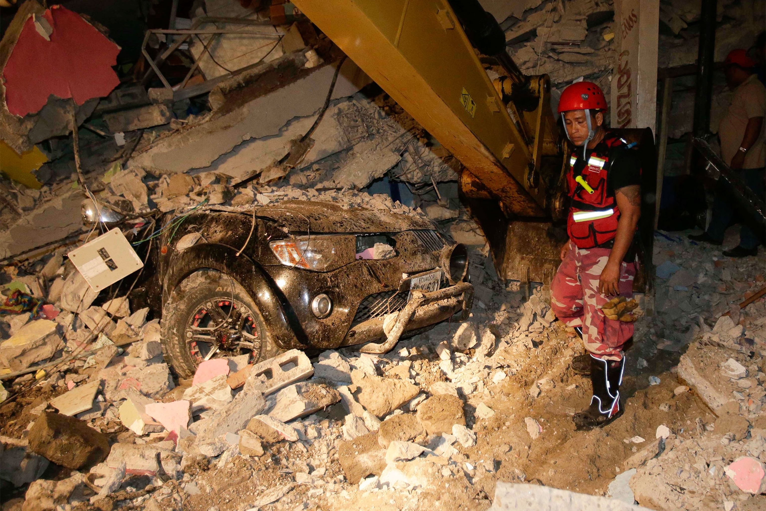 a rescue worker near a car that was crushed in an earthquake