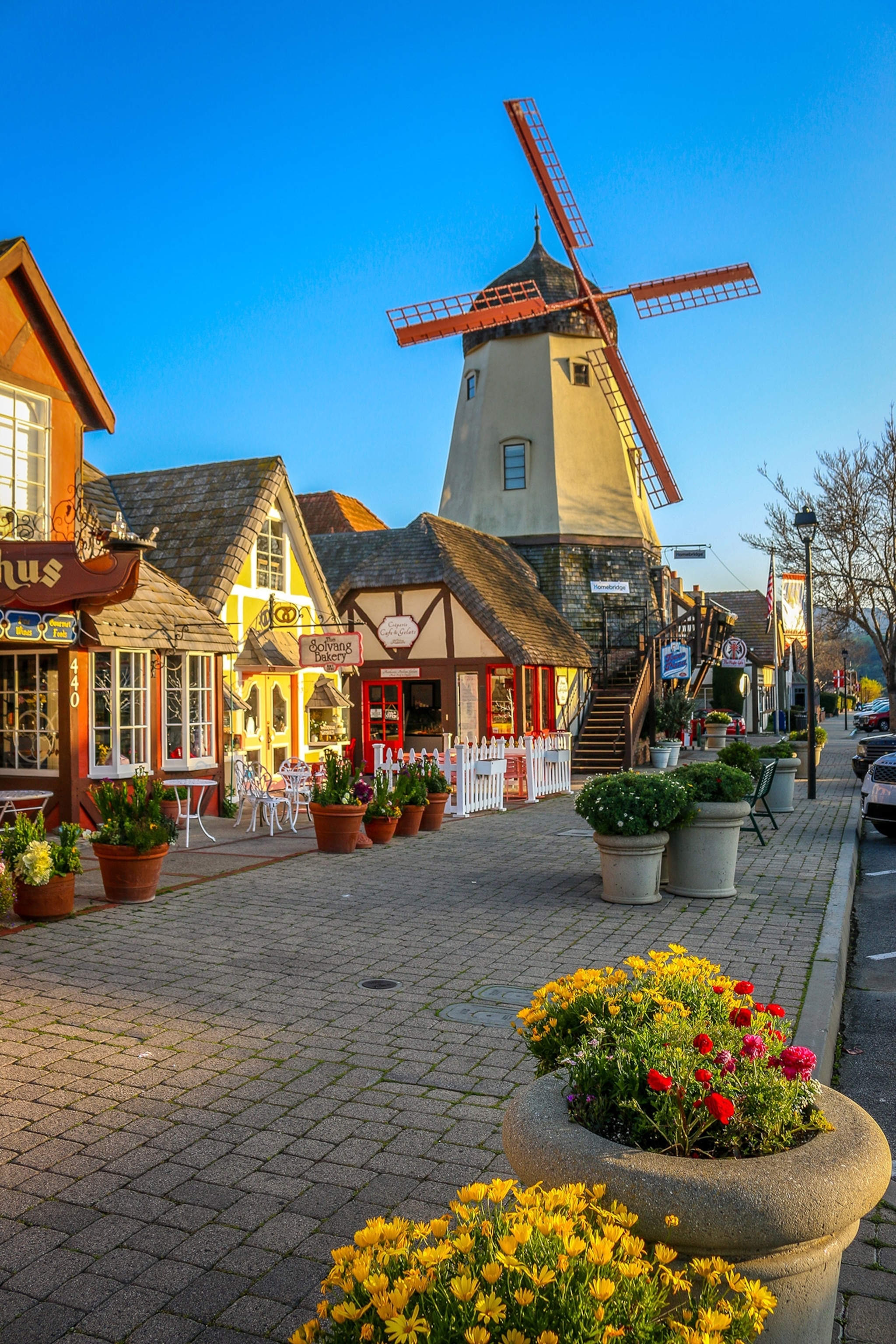 A windmill towers over a small town street with shopfronts