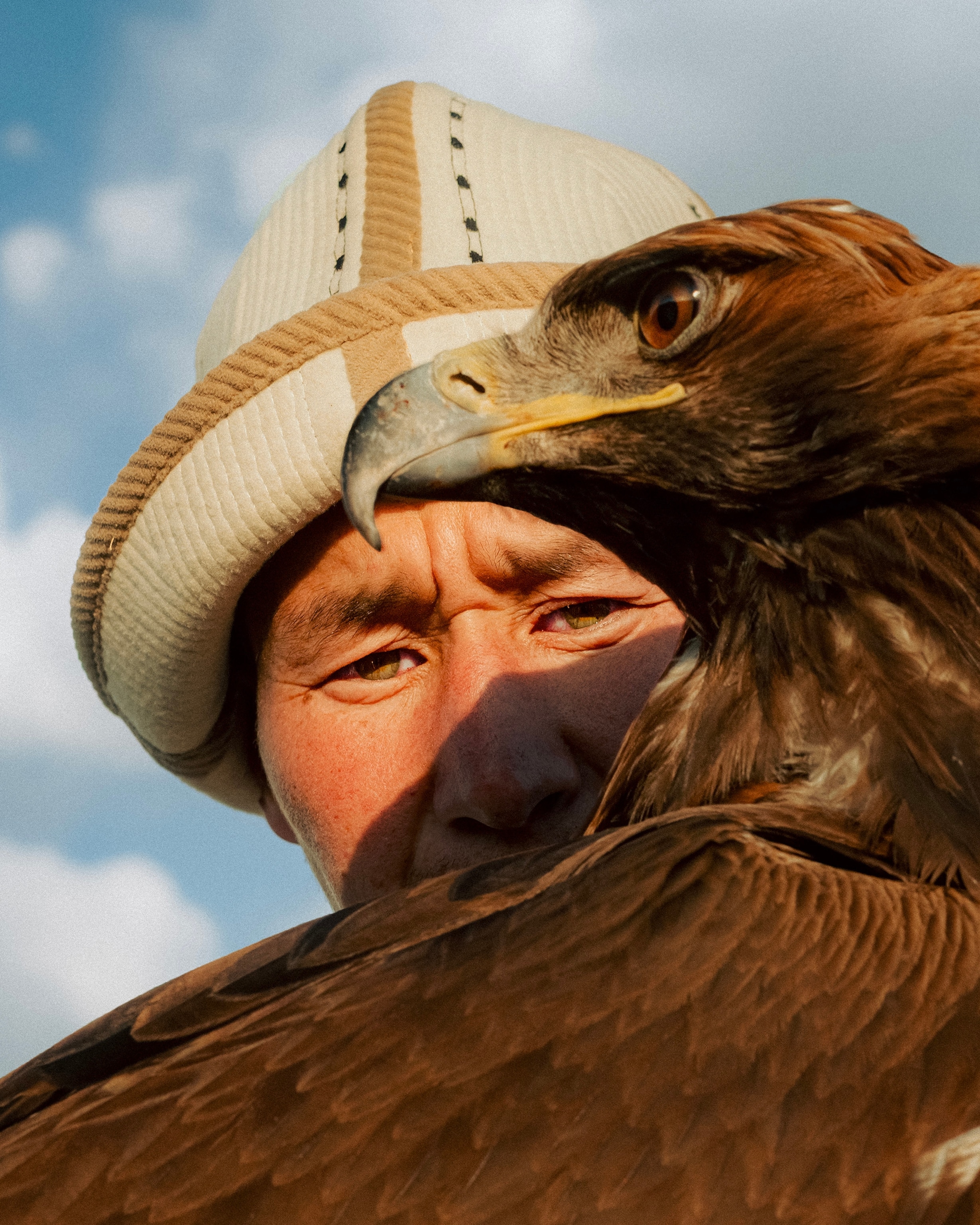 A man stares ahead behind a large brown eagle.