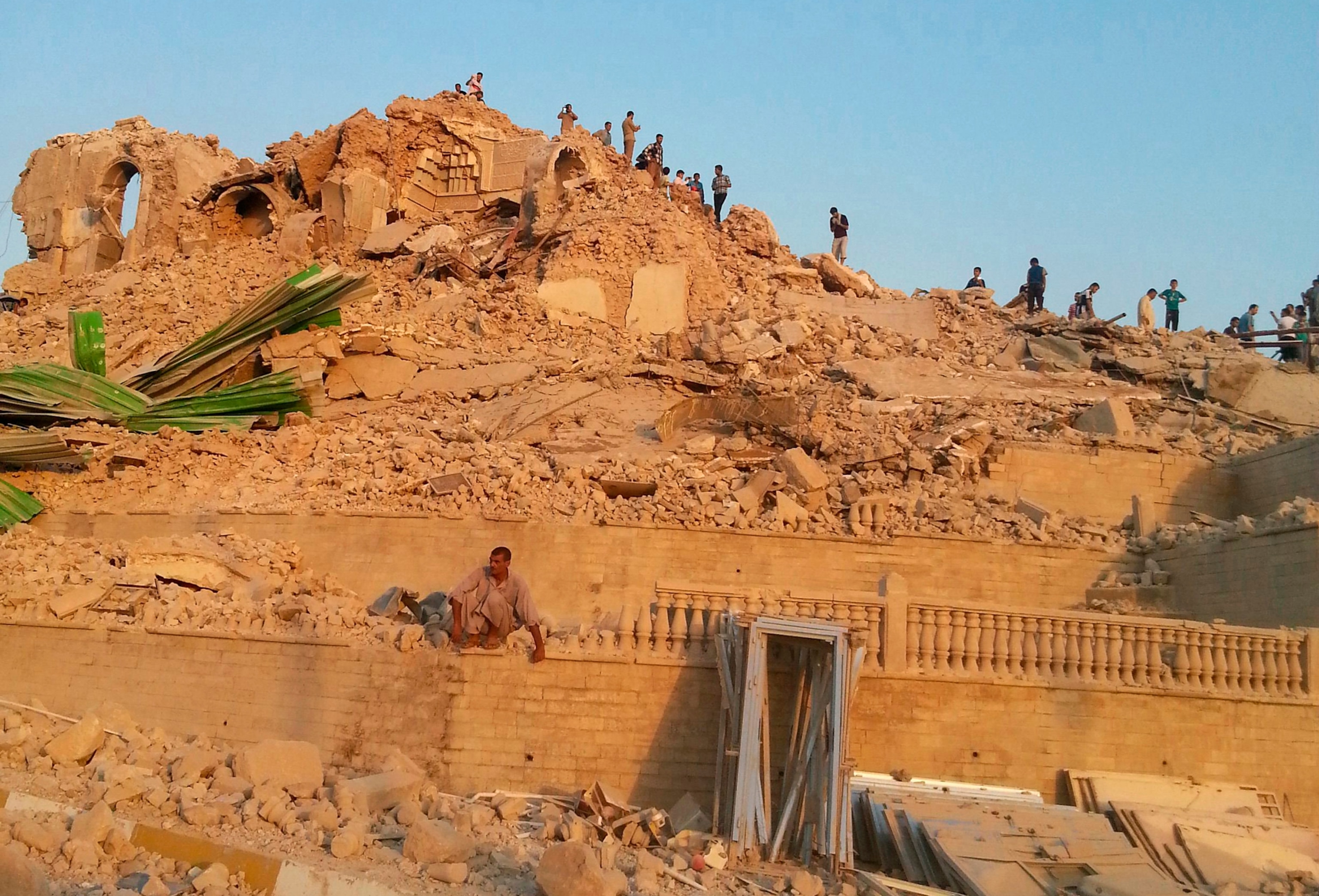 people walking through the rubble of the Prophet Younis Mosque
