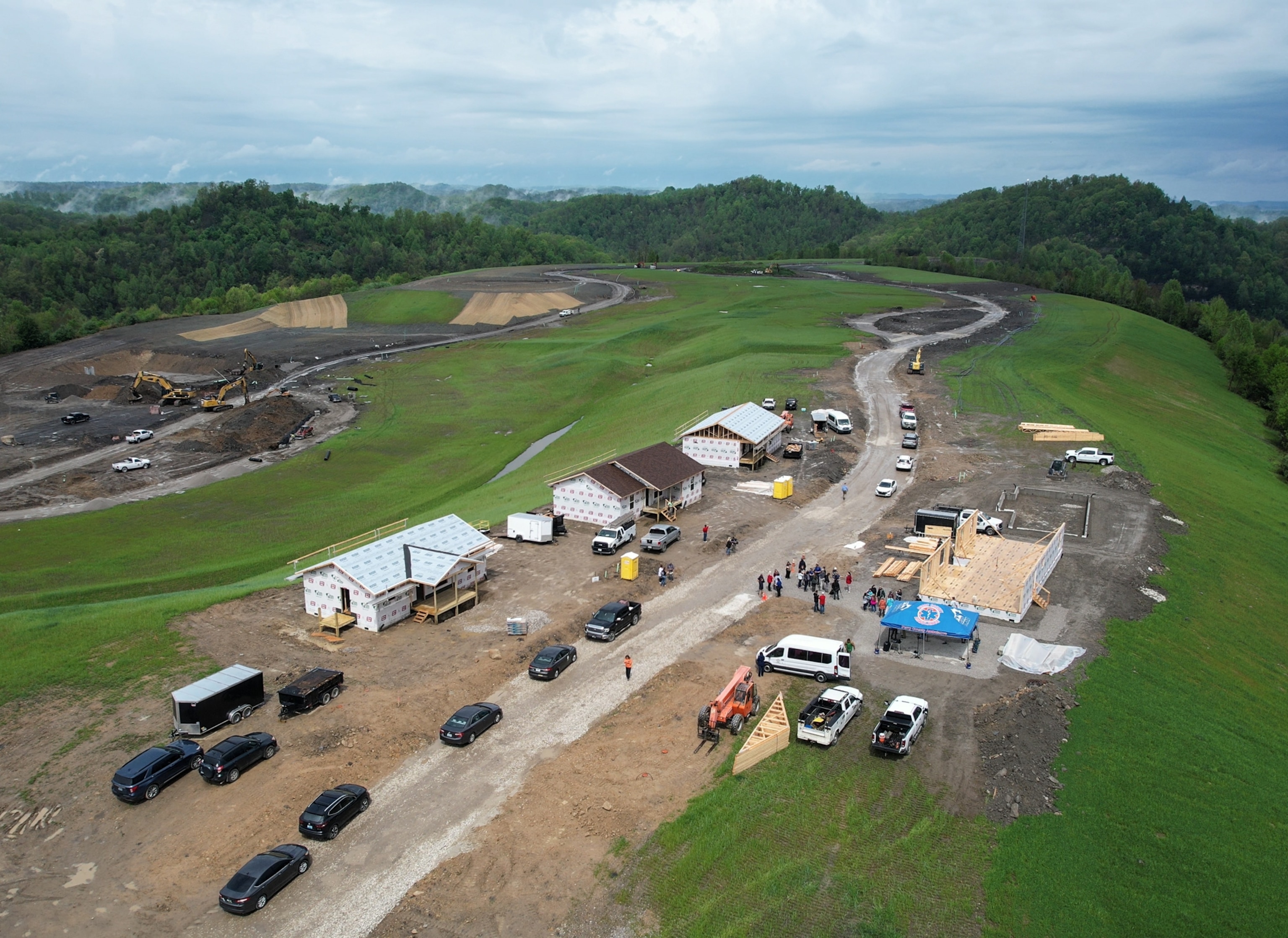 Drone view of houses contraction on green hilltop.