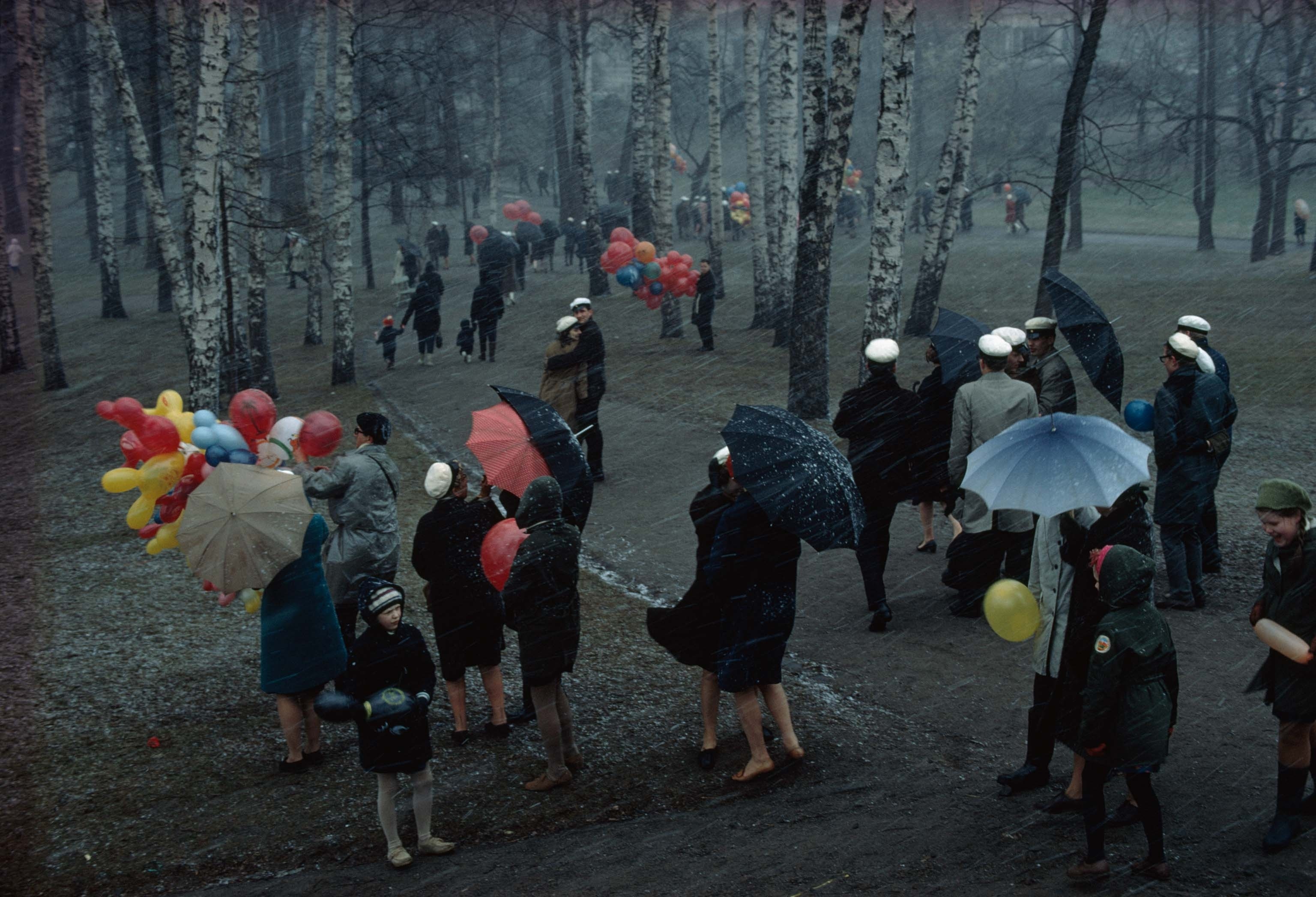 people walking in snow with umbrellas and balloons