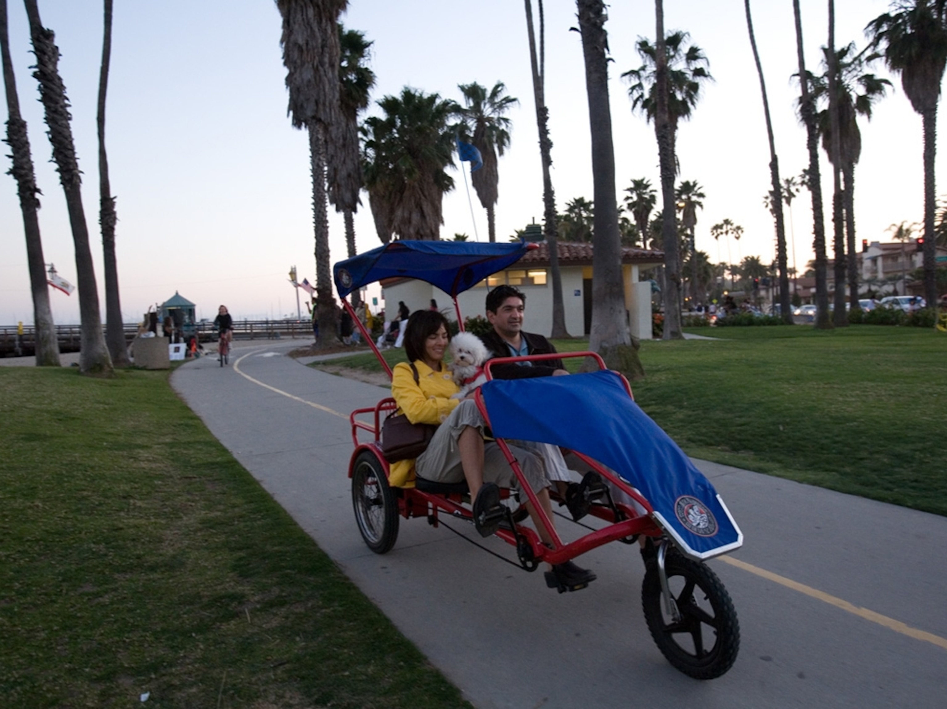 couple with dog riding three wheeler on the beachwalk in santa barbara