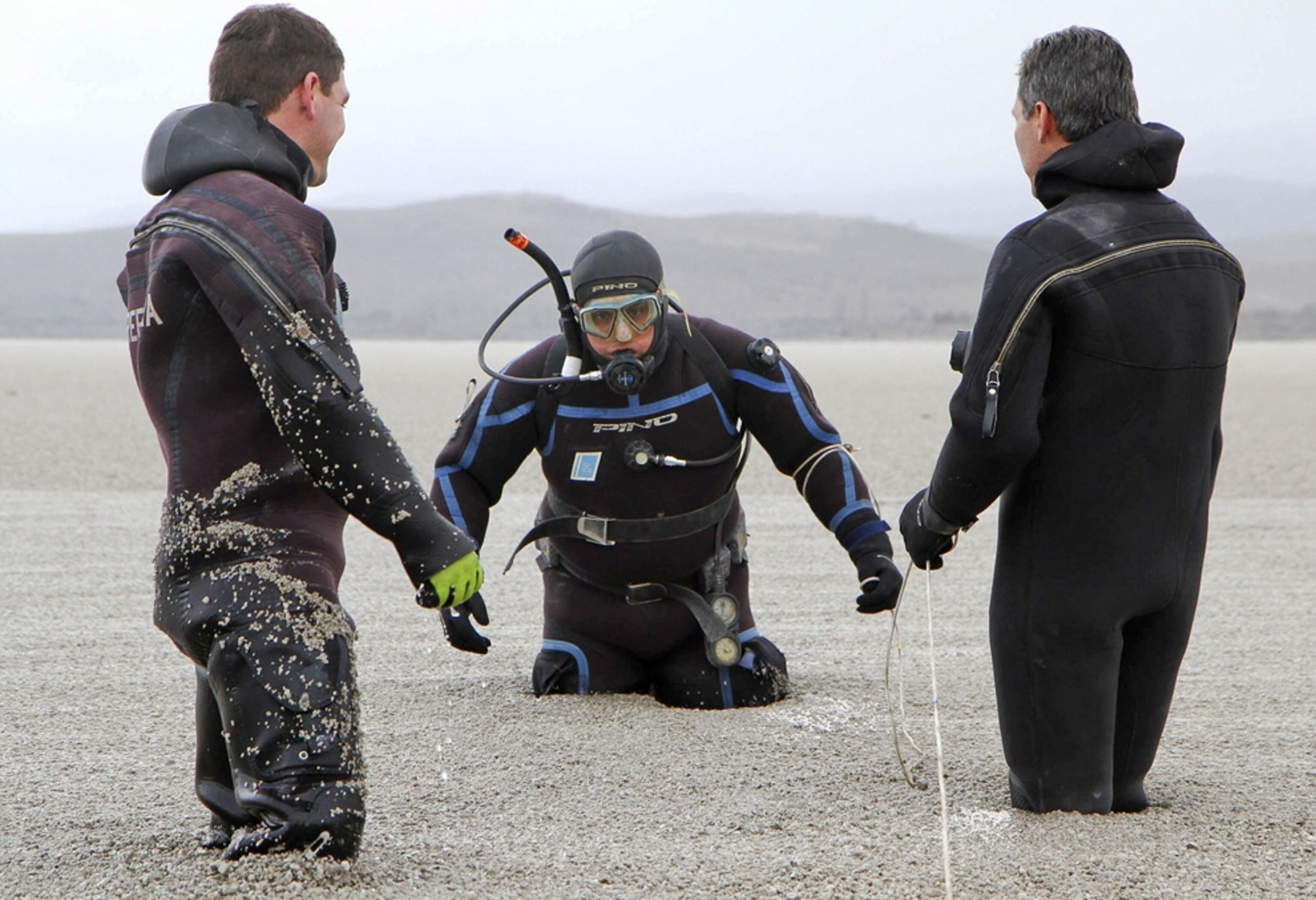 divers standing in an ashy lake in Argentina