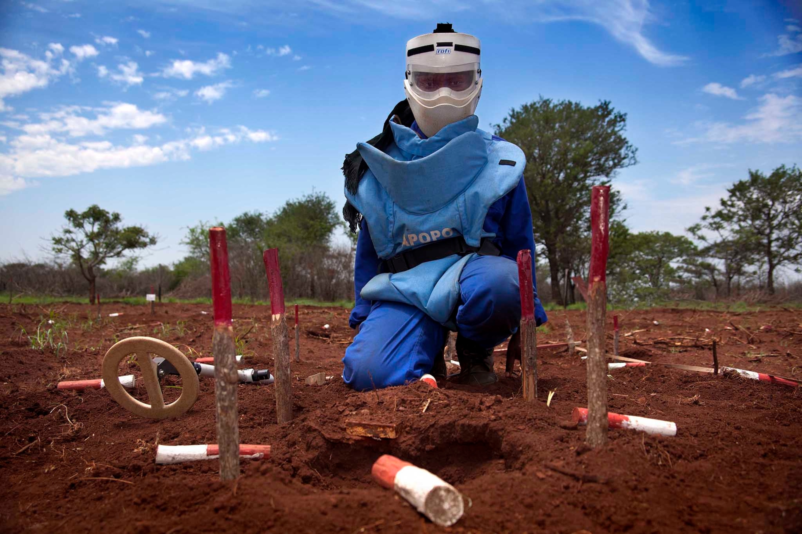 Flora Armando Chipossa Tenho uses a metal detector to search for land mines in southern Mozambique. Government forces placed mines around major infrastructure like these power lines to protect them from sabotage during the country’s long civil war.
