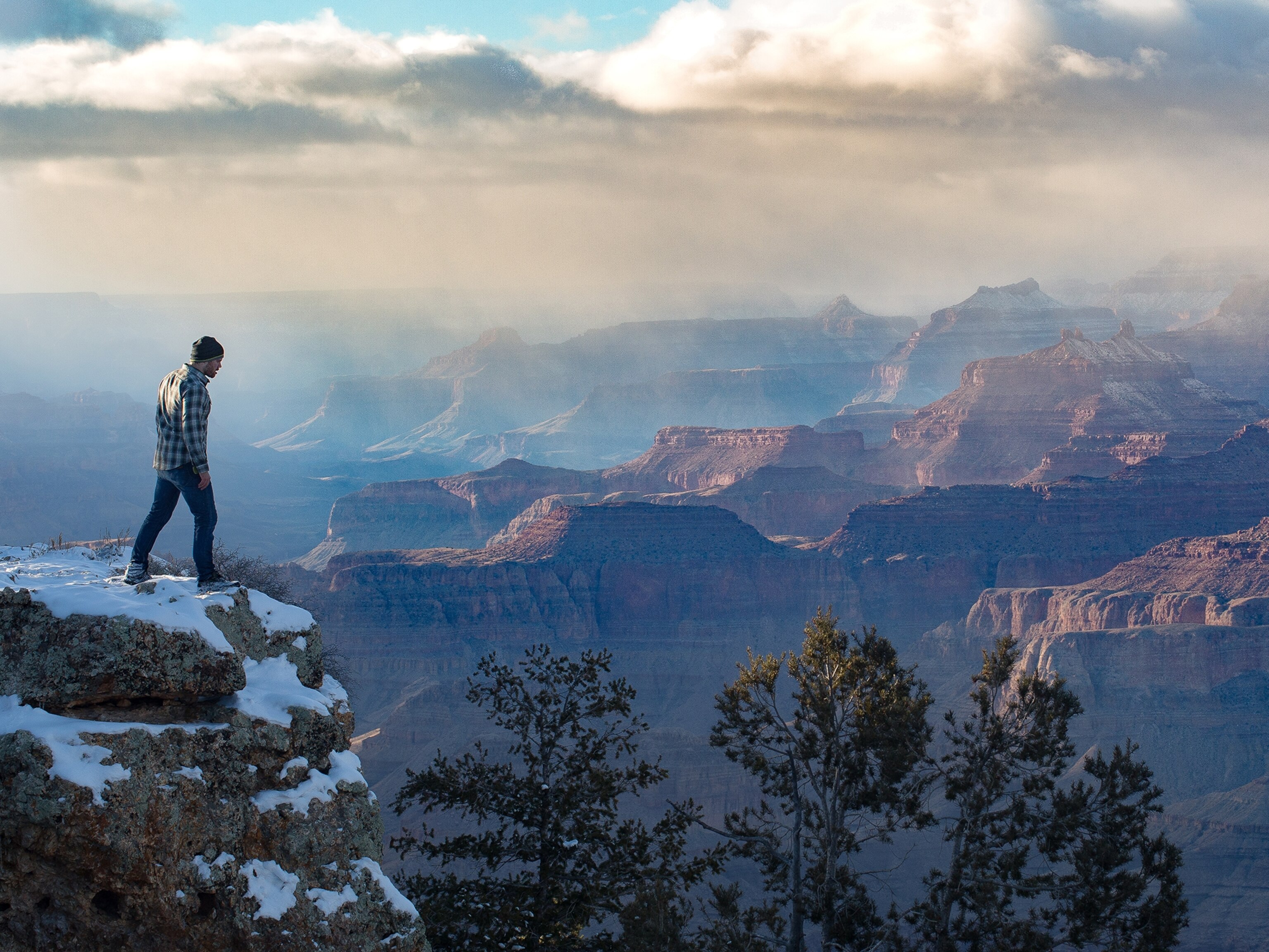 a man standing on the edge of the canyon rim of the Grand Canyon in winter