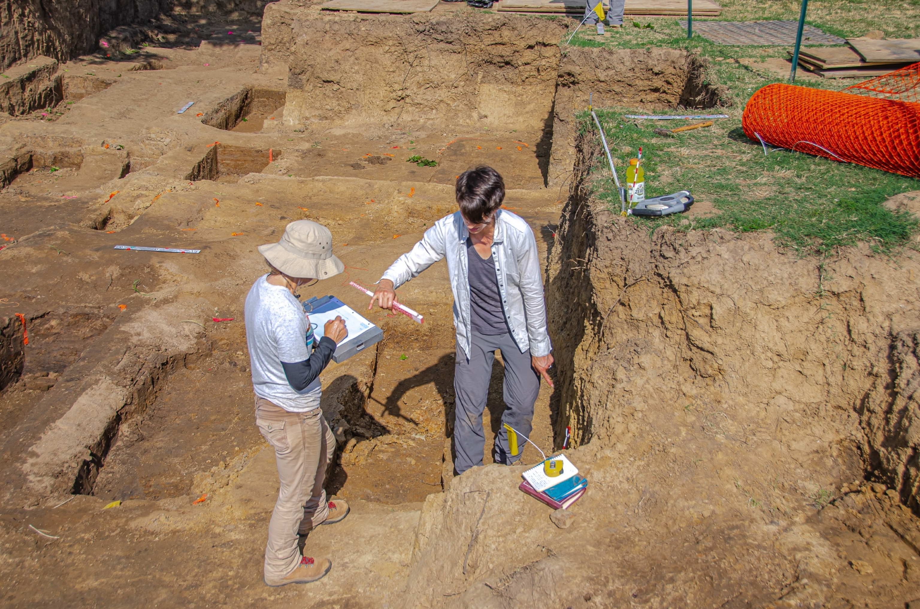 Two women look at a clipboard in front of mass graves