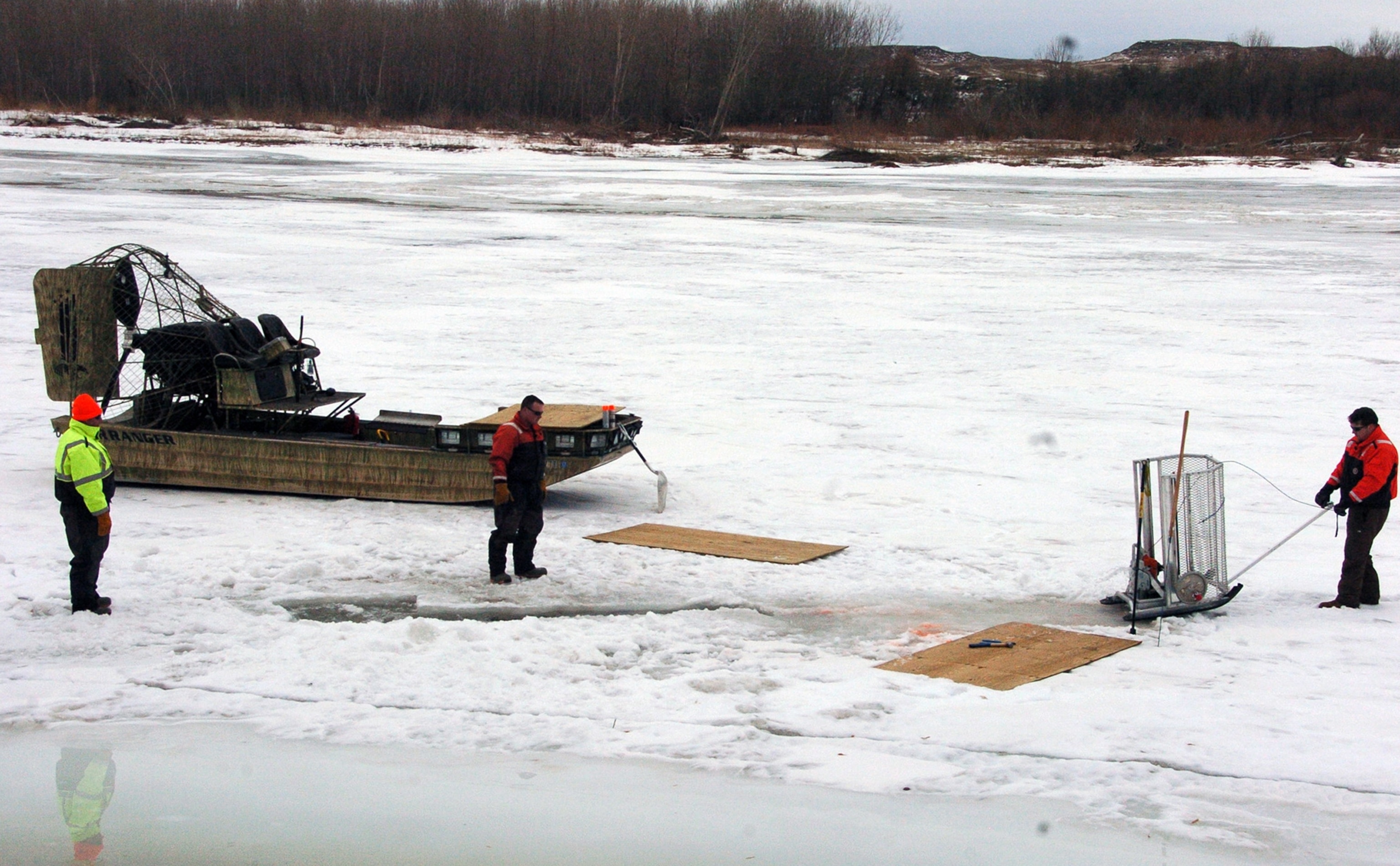 cleanup workers cutting holes into the ice on the Yellowstone River near Crane, Montana